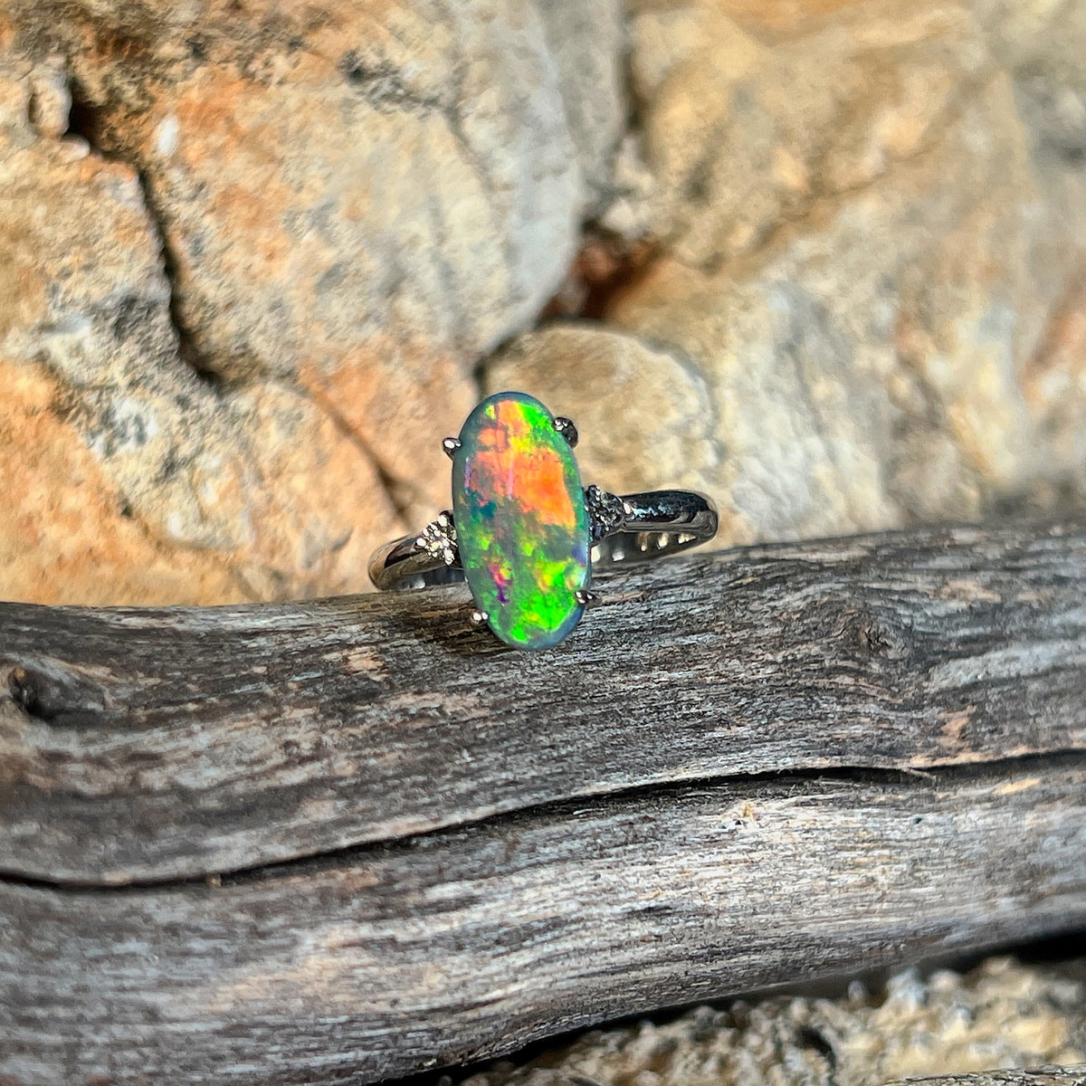 Solid Australian black opal ring, 1.4ct oval stone with green and red flashes in 18kt white gold