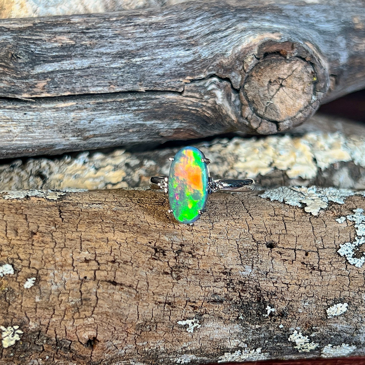 Close view of an oval Australian black opal in an 18kt white gold ring, green and yellow colour