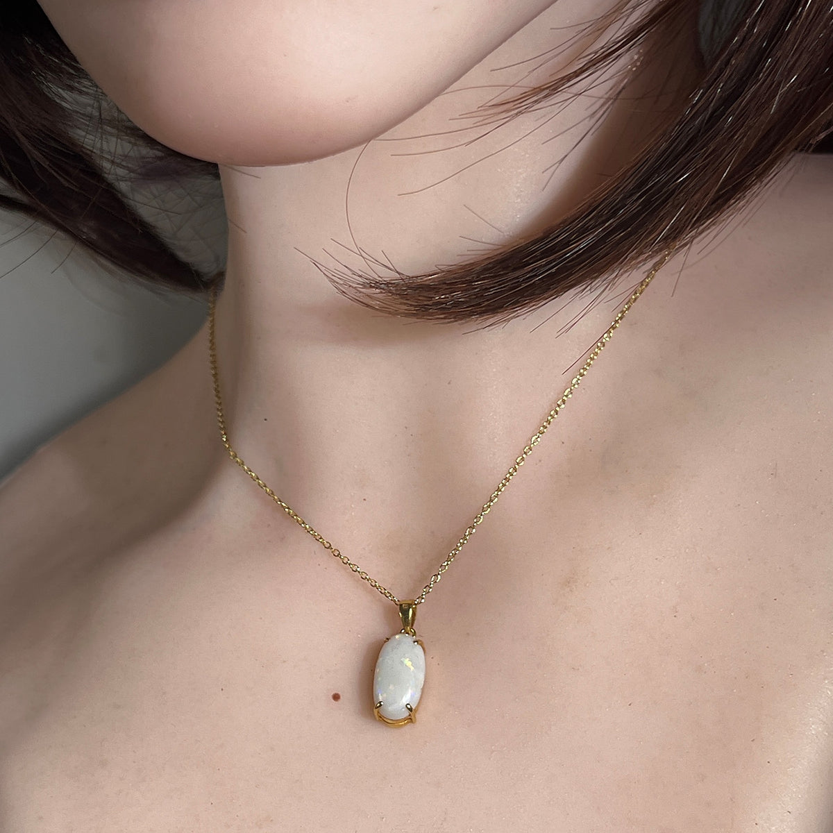 Australian white opal pendant worn, 2.3ct oval white opal claw set in 18kt yellow gold