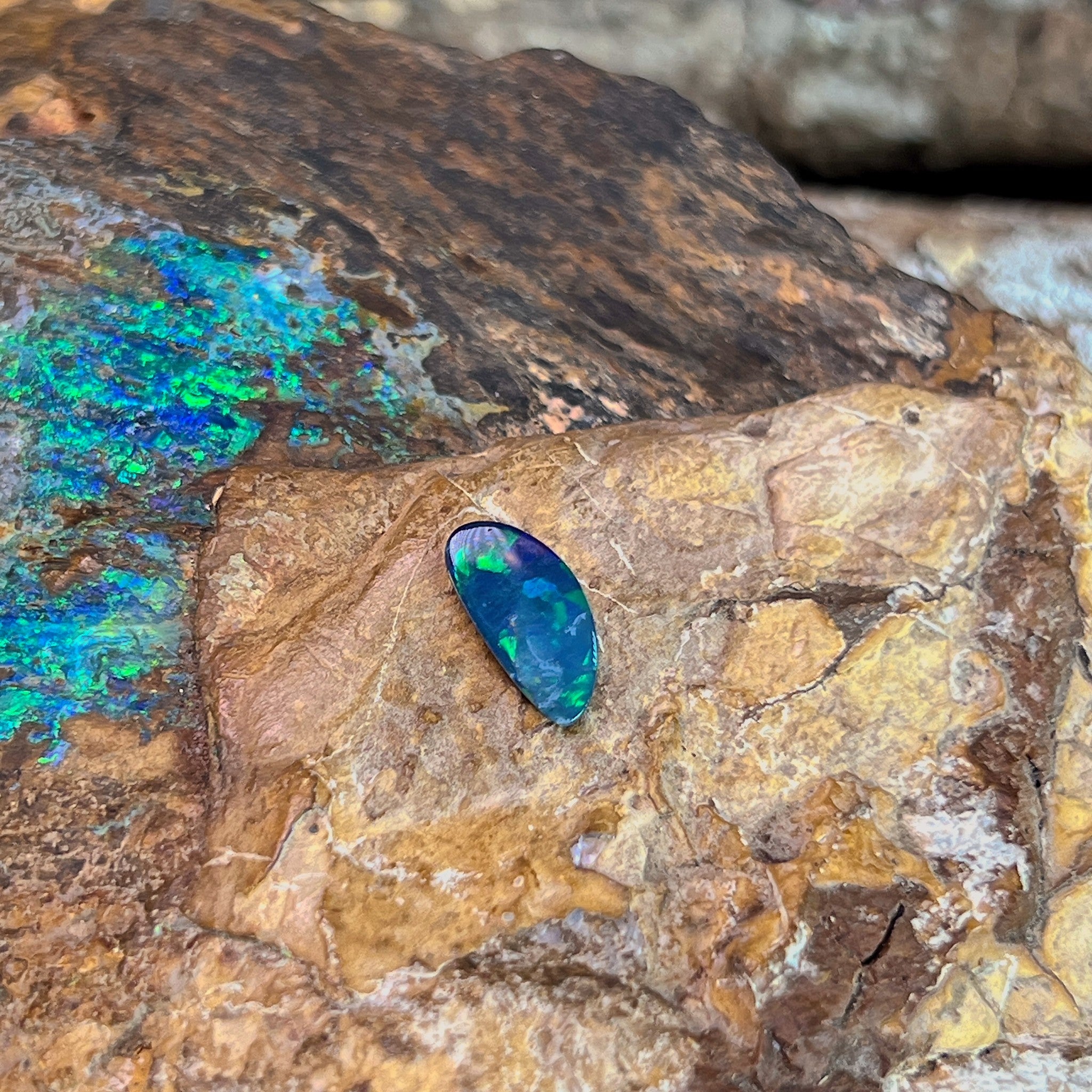 0.88ct Australian opal doublet on ironstone, green and blue along an elongated freeform