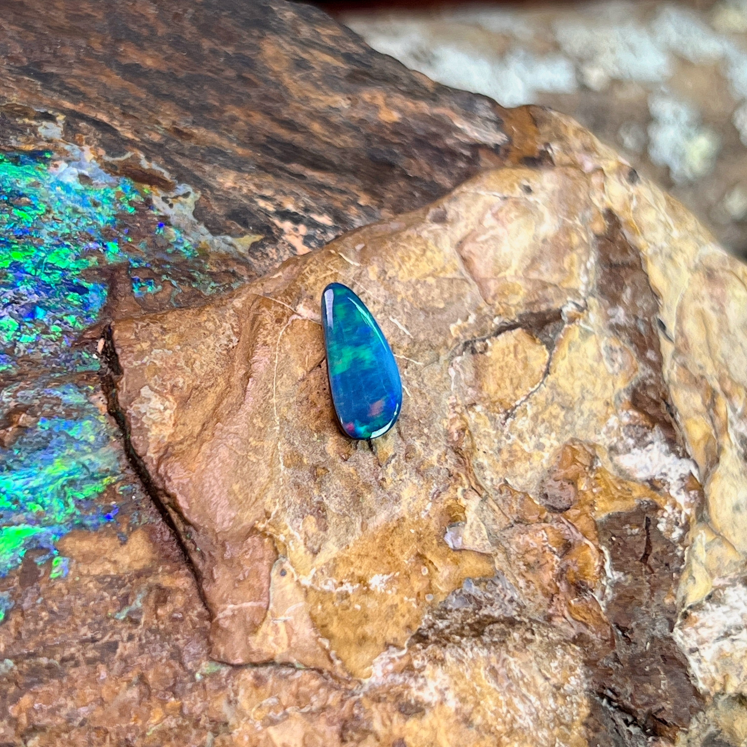 Green fire in an elongated 0.74ct Australian opal doublet, 11.2x5.4mm, on weathered rock