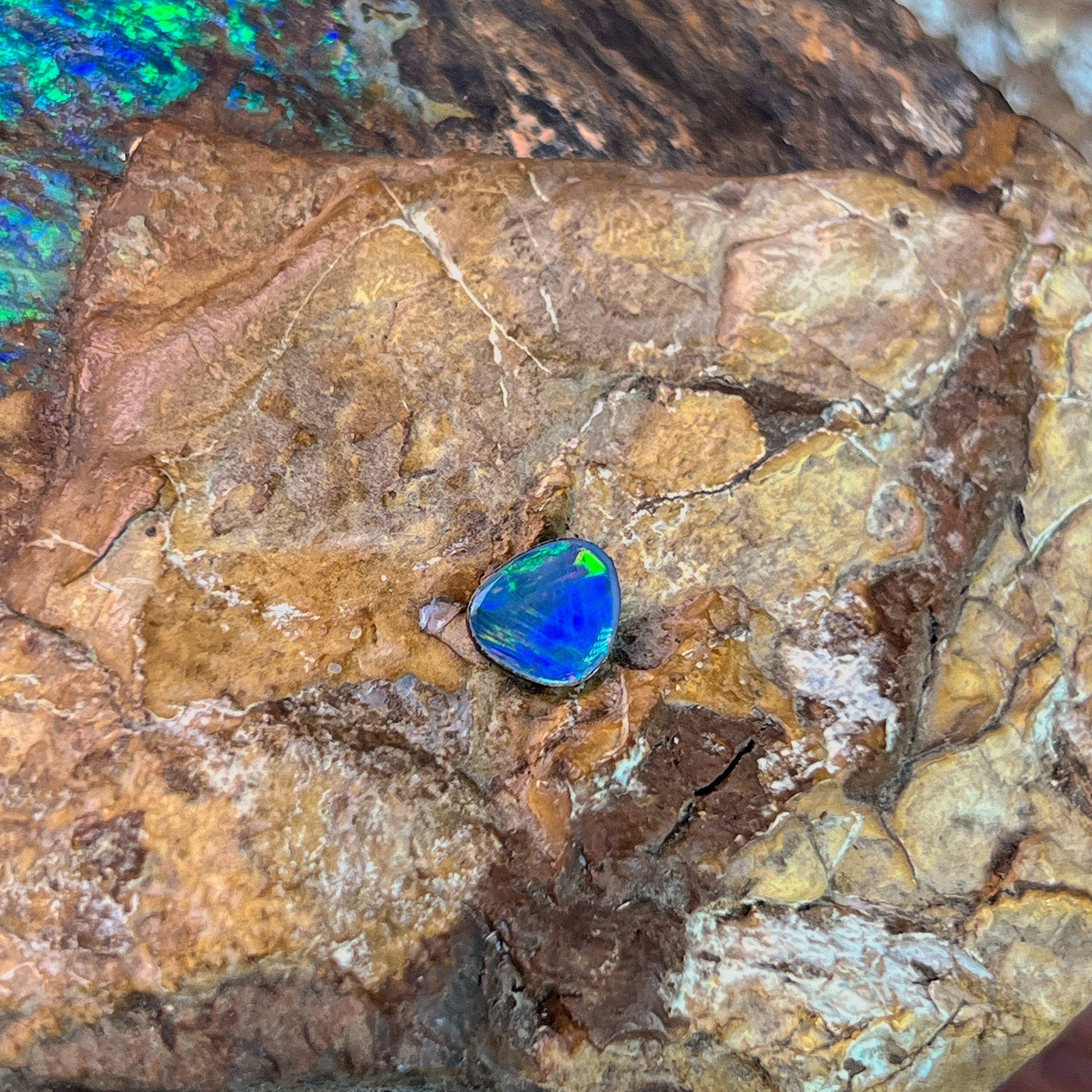 Green and yellow fire in a 0.70ct Australian opal doublet, 7.7x6.4mm, on weathered rock