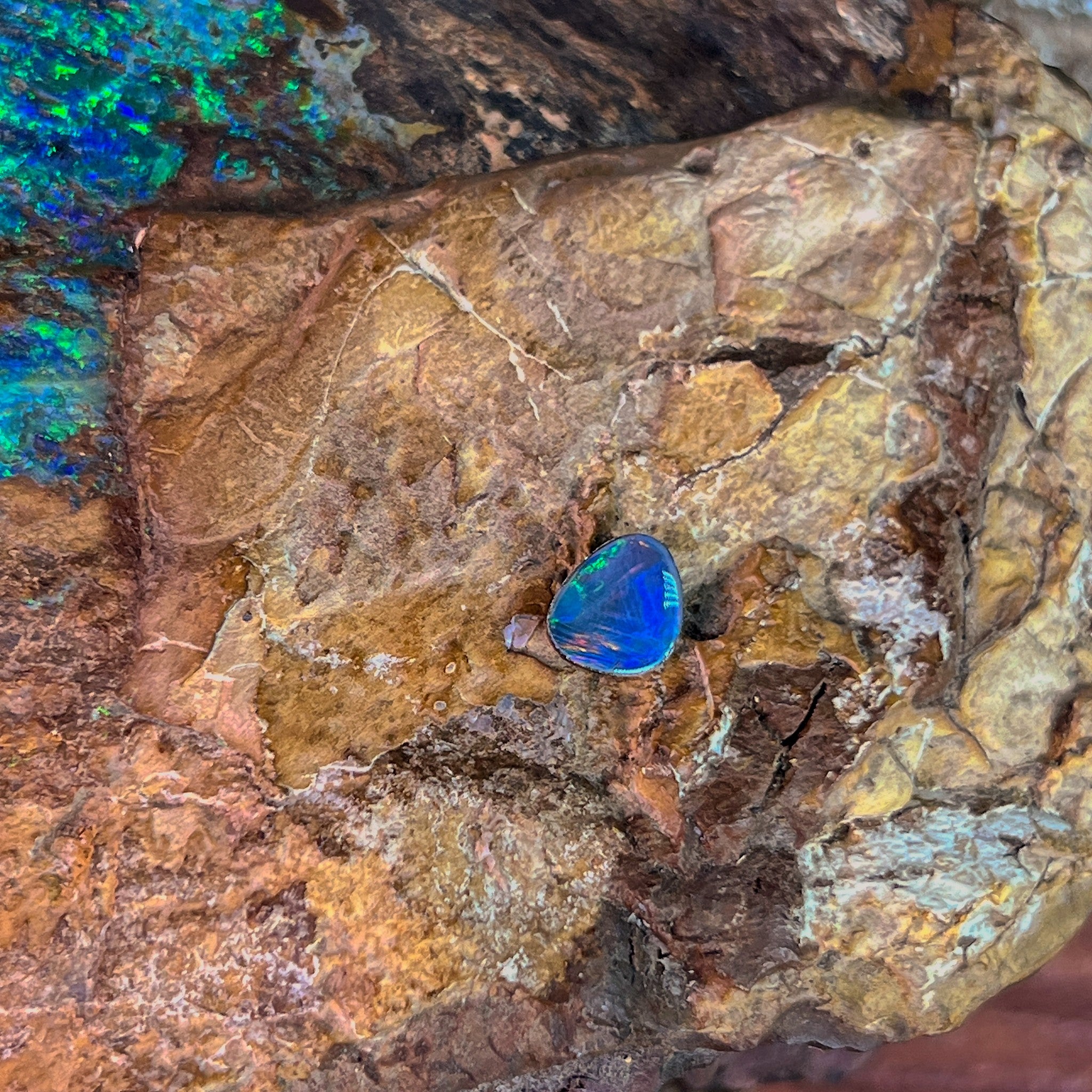 Blue violet body lit with green, a freeform 0.70ct Australian opal doublet on rock
