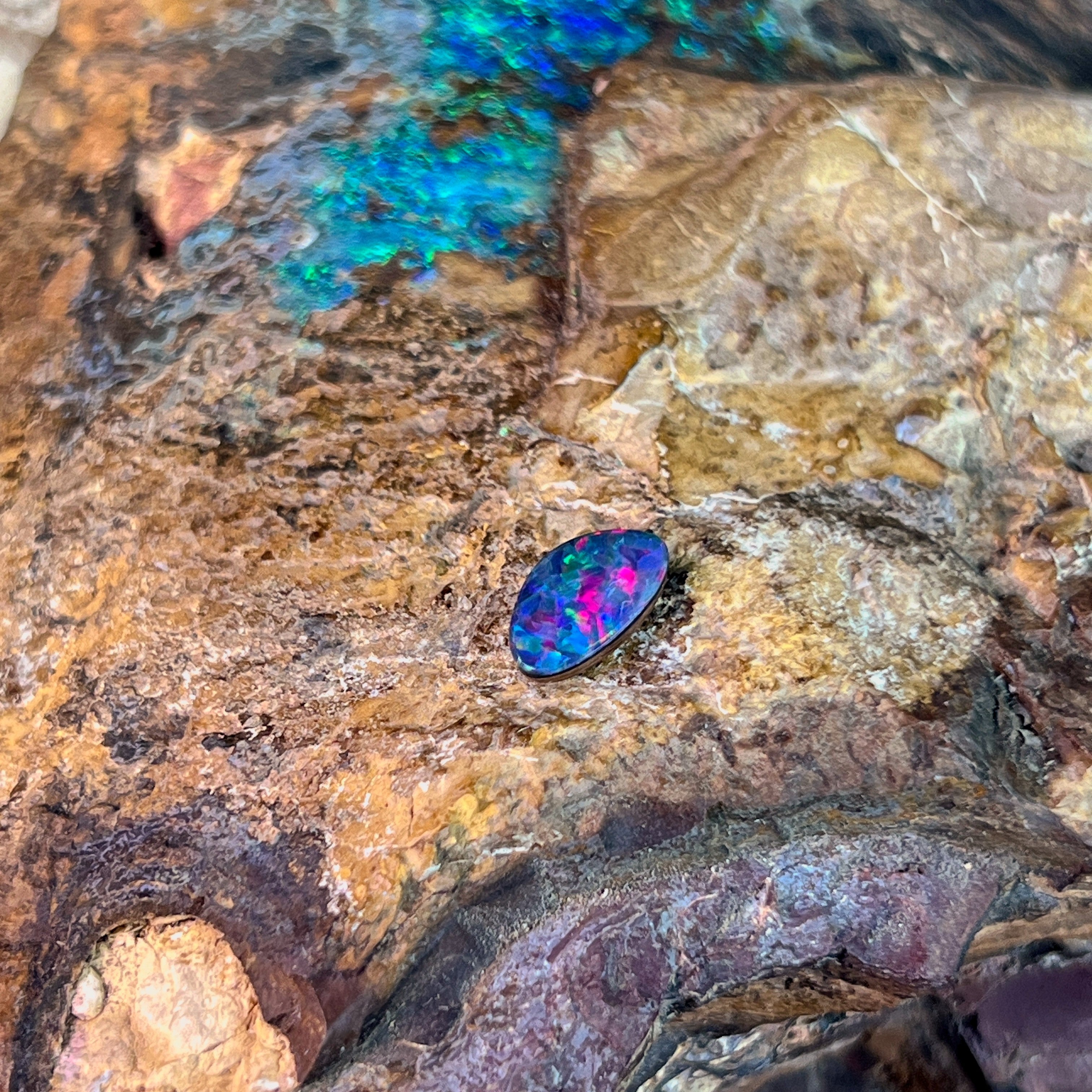 Rose red and green fire in a 0.91ct Australian opal doublet, 9.3x5.7mm, on weathered rock