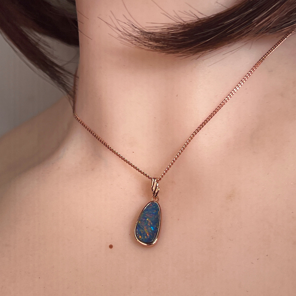 red, blue, green and violet Australian opal doublet pendant worn at the neck, rose gold-plated silver, 15 x 7.5mm