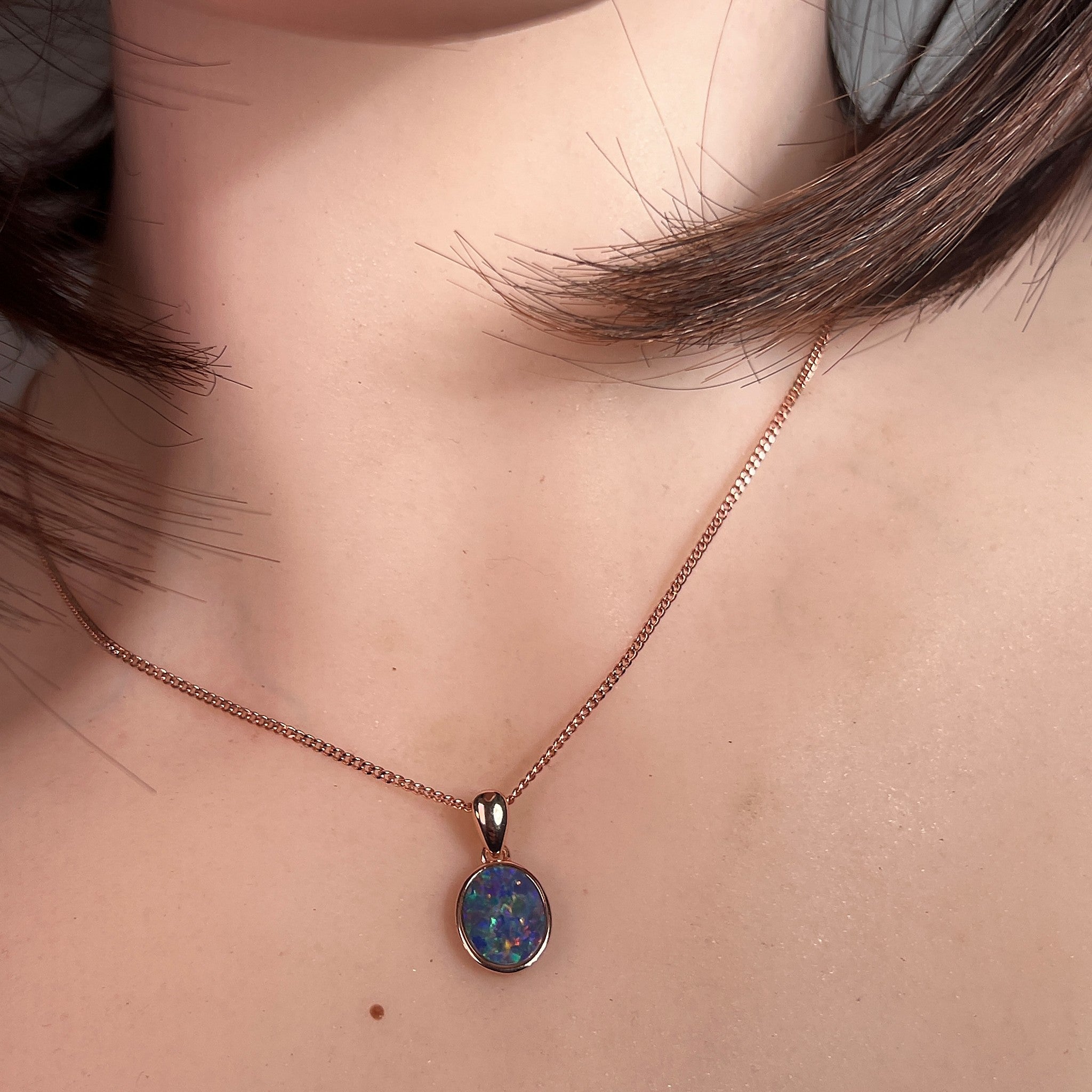 oval Australian opal doublet pendant in rose gold-plated silver, worn at the neck