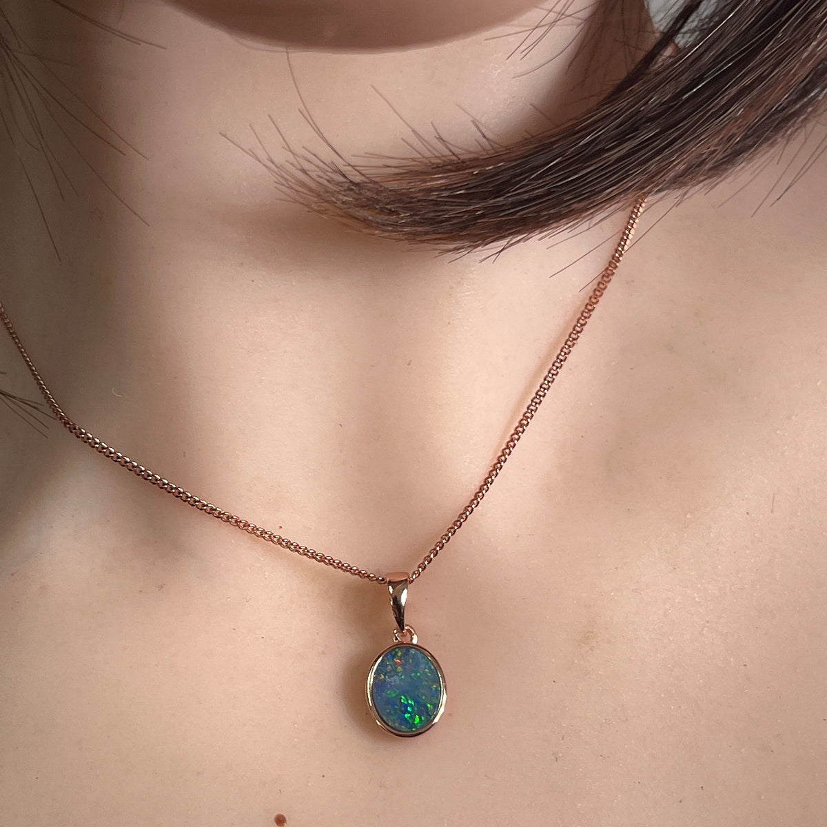 Australian opal doublet pendant worn at the neck, green, red, blue and yellow play-of-colour