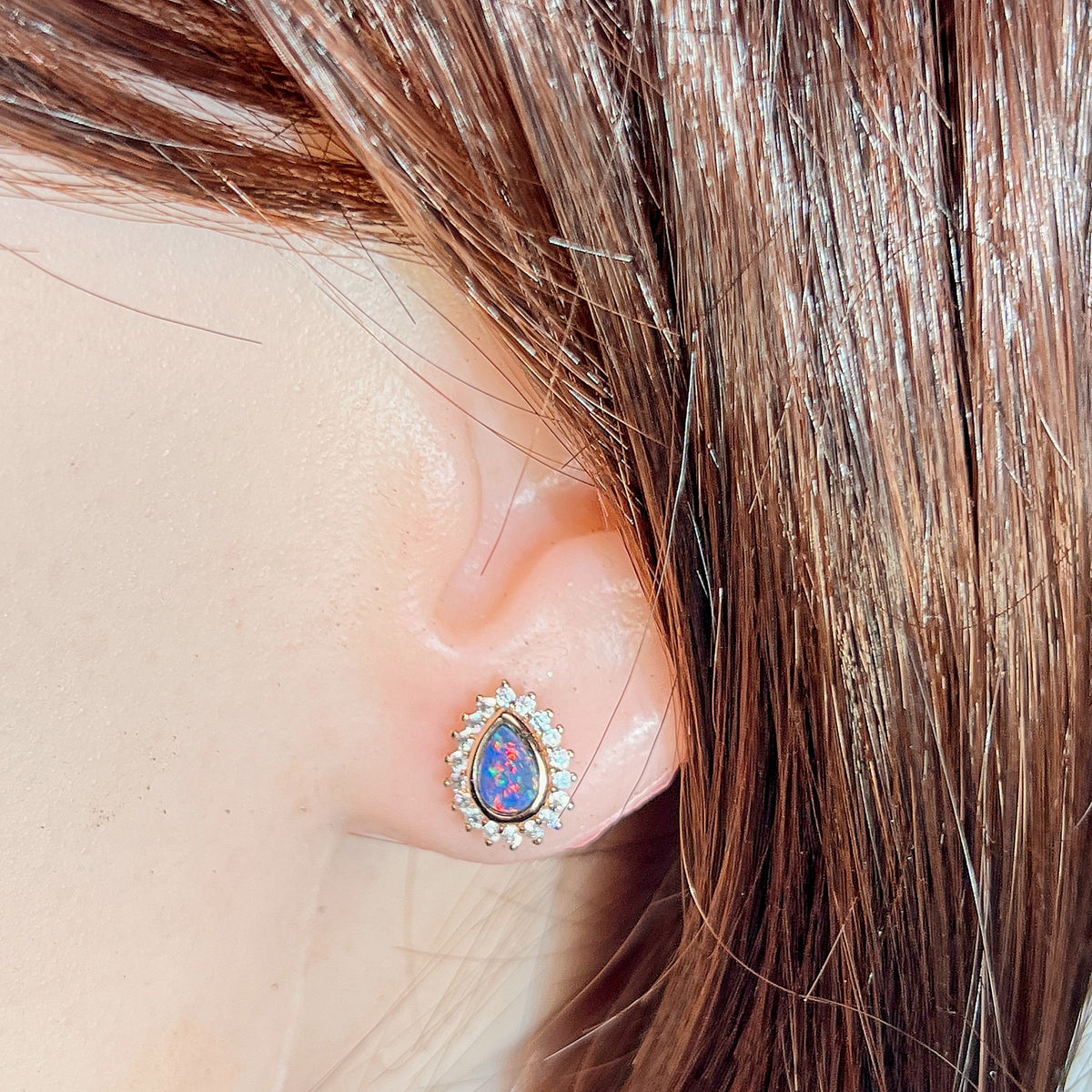 Australian opal doublet earrings worn on the ear, red, blue and green play-of-colour