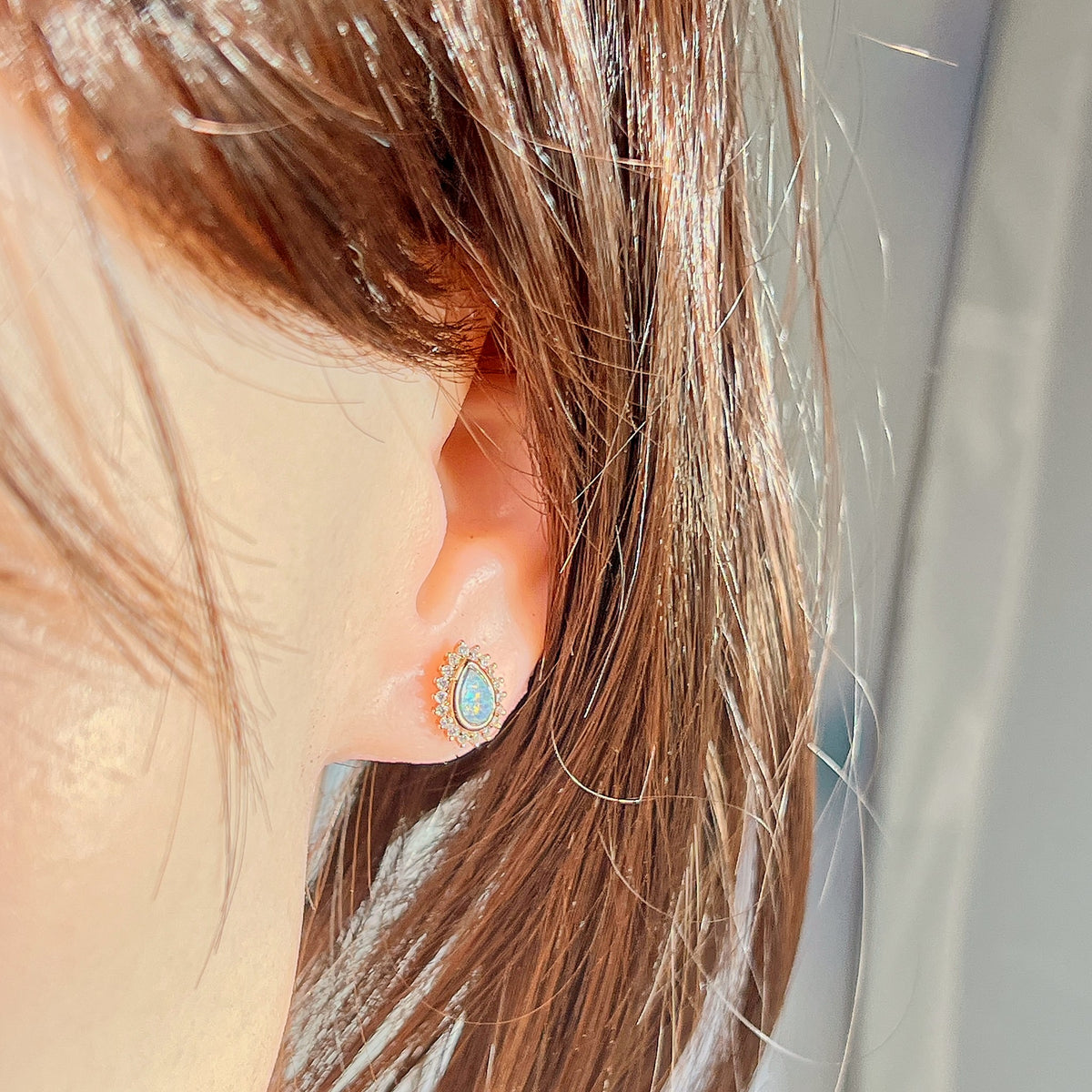 7 x 5mm pear-shaped Australian opal doublet earrings worn on the ear, rose gold-plated silver