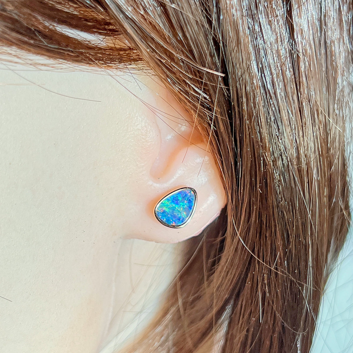 triangular Australian opal doublet earrings in rose gold-plated silver, worn on the ear