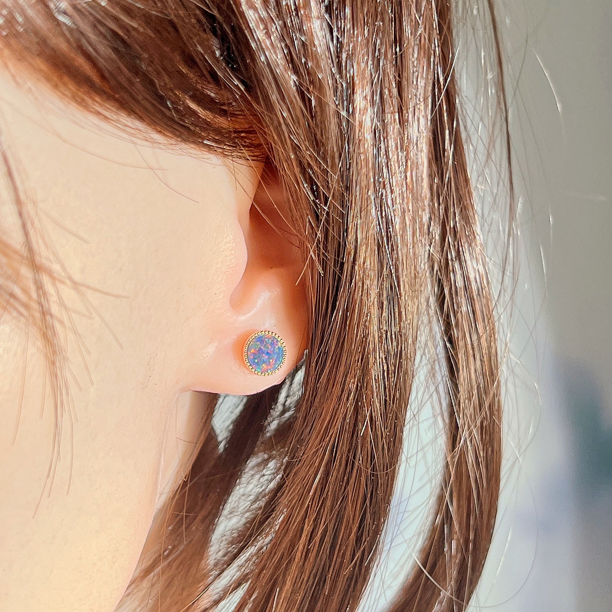 Australian opal triplet earrings worn on the ear, red, blue and green play-of-colour