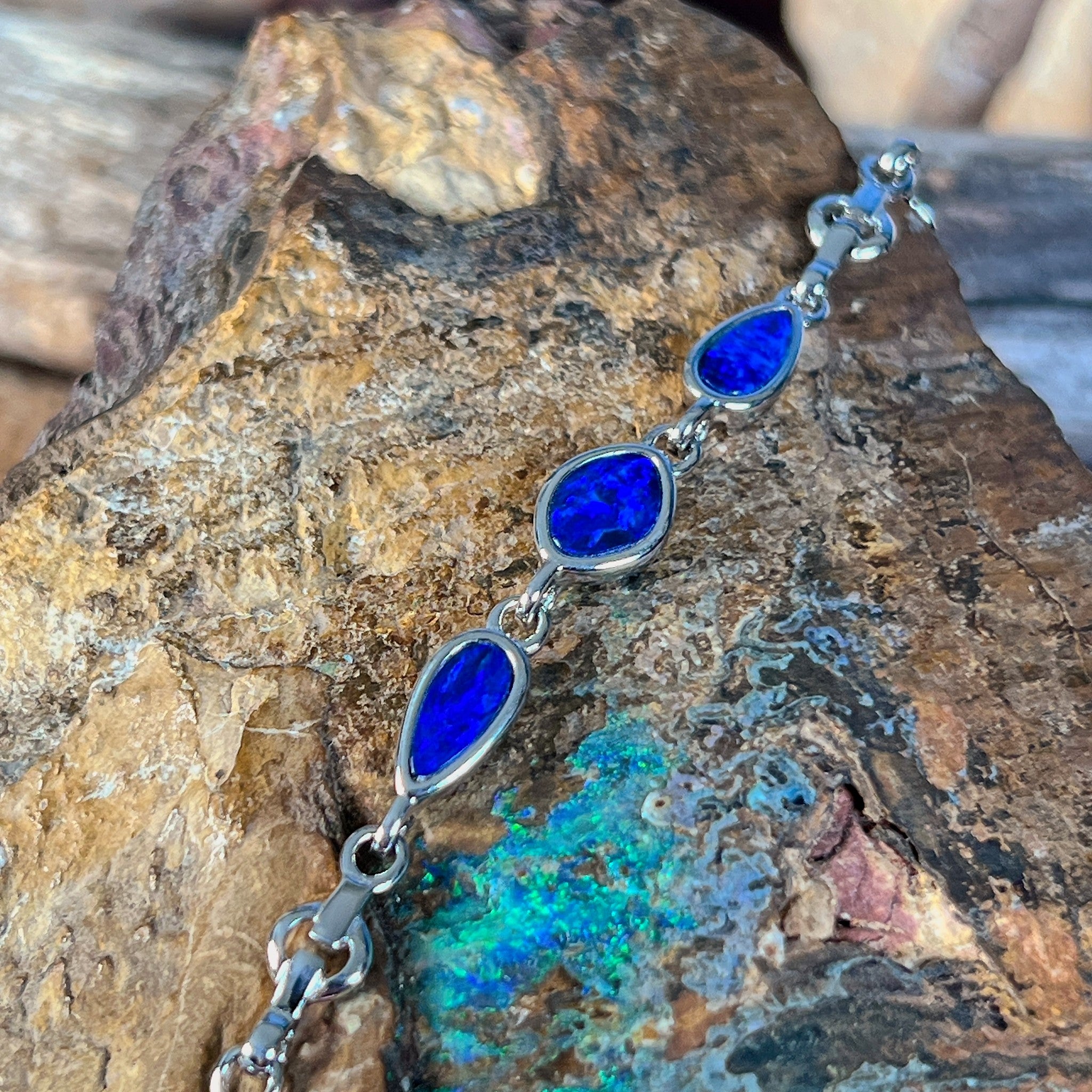 Sterling silver bracelet with three opal doublets on rock, the opal doublets catching the light