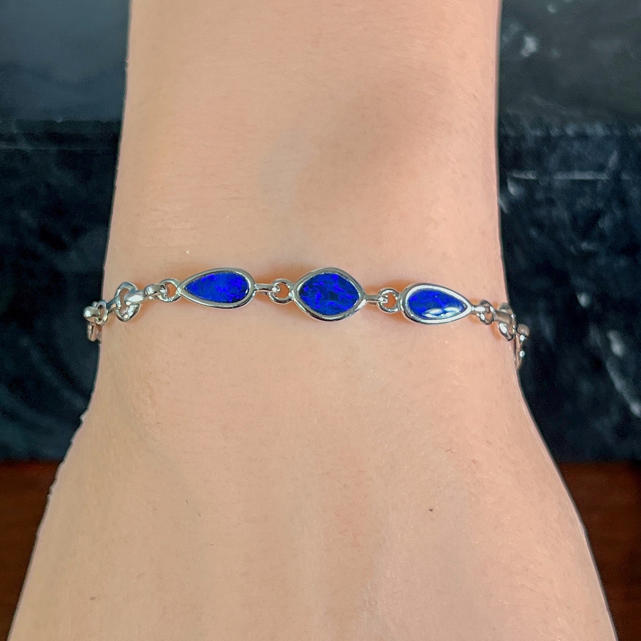 Sterling silver bracelet with three opal doublets worn on the wrist, viewed along the arm