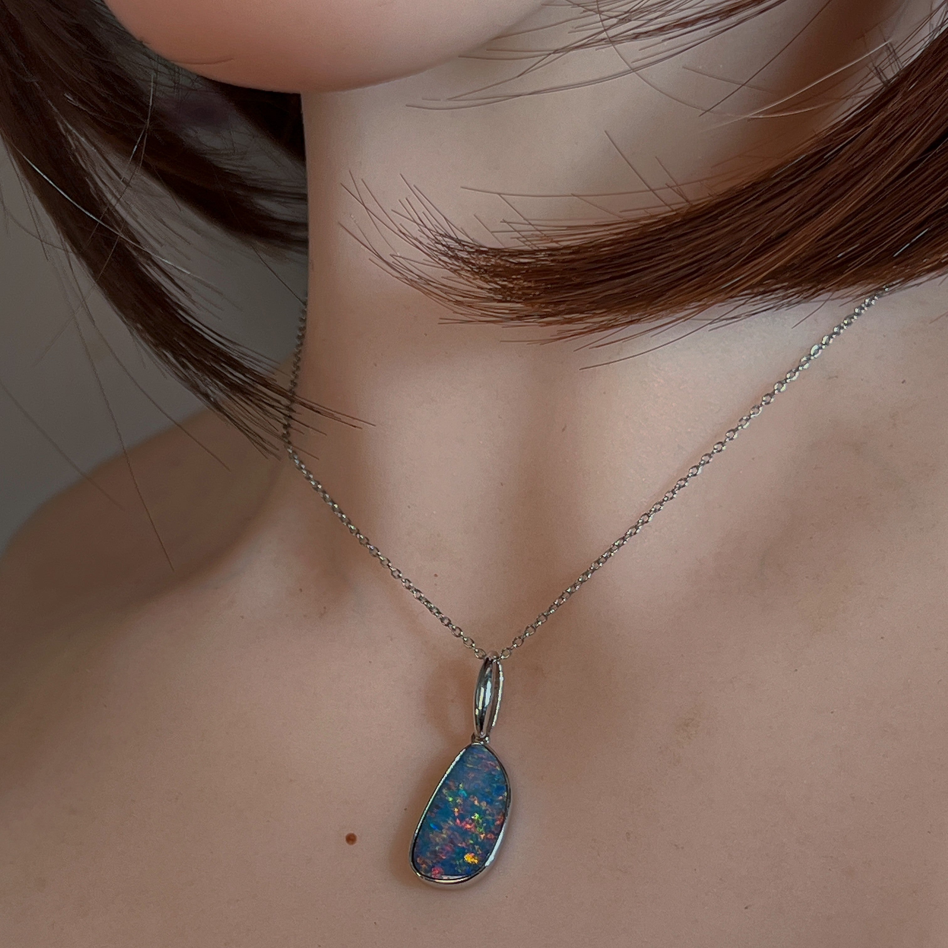 Freeform opal doublet pendant in silver worn on a fine chain at the neckline