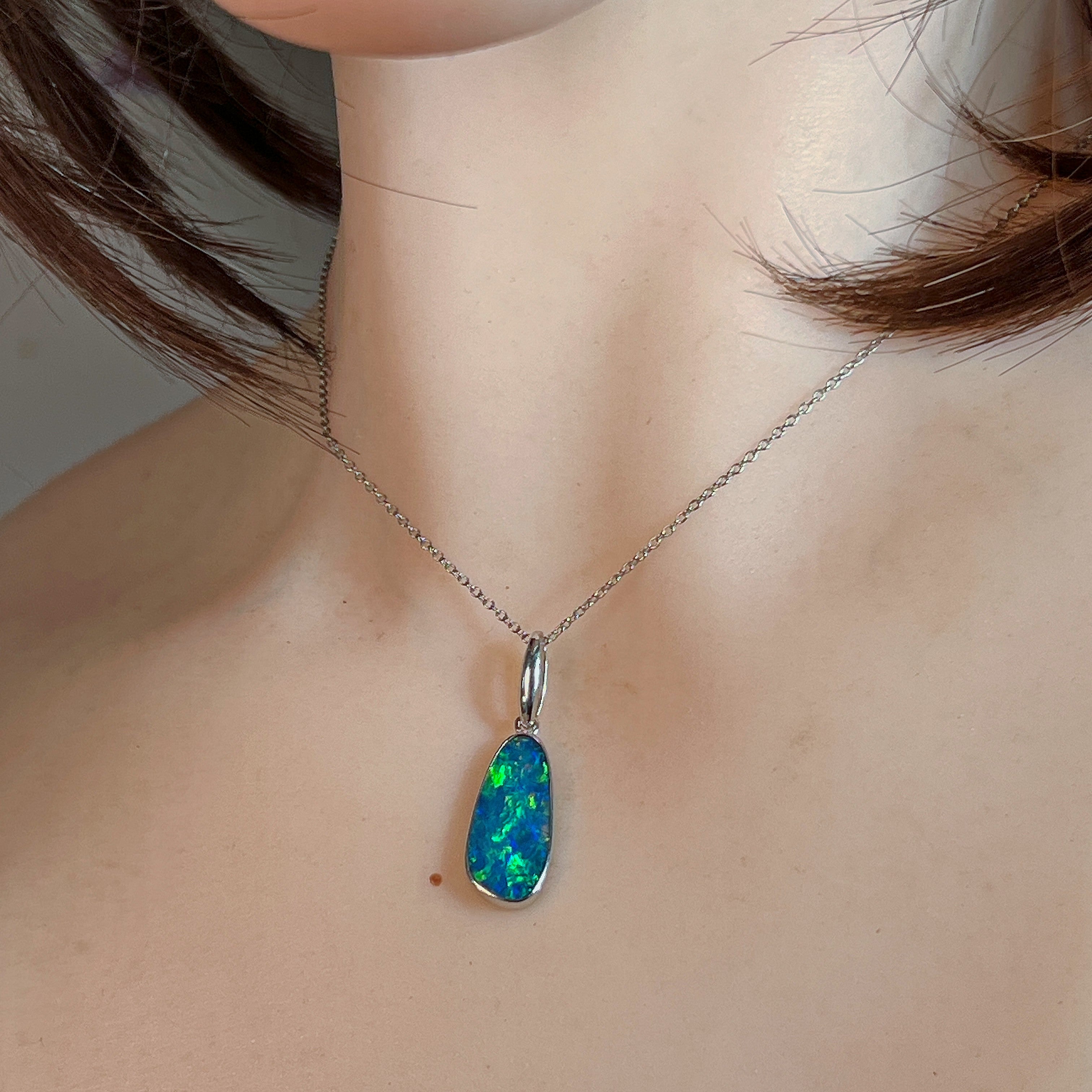Green and blue opal doublet pendant in silver worn on a fine chain at the neckline