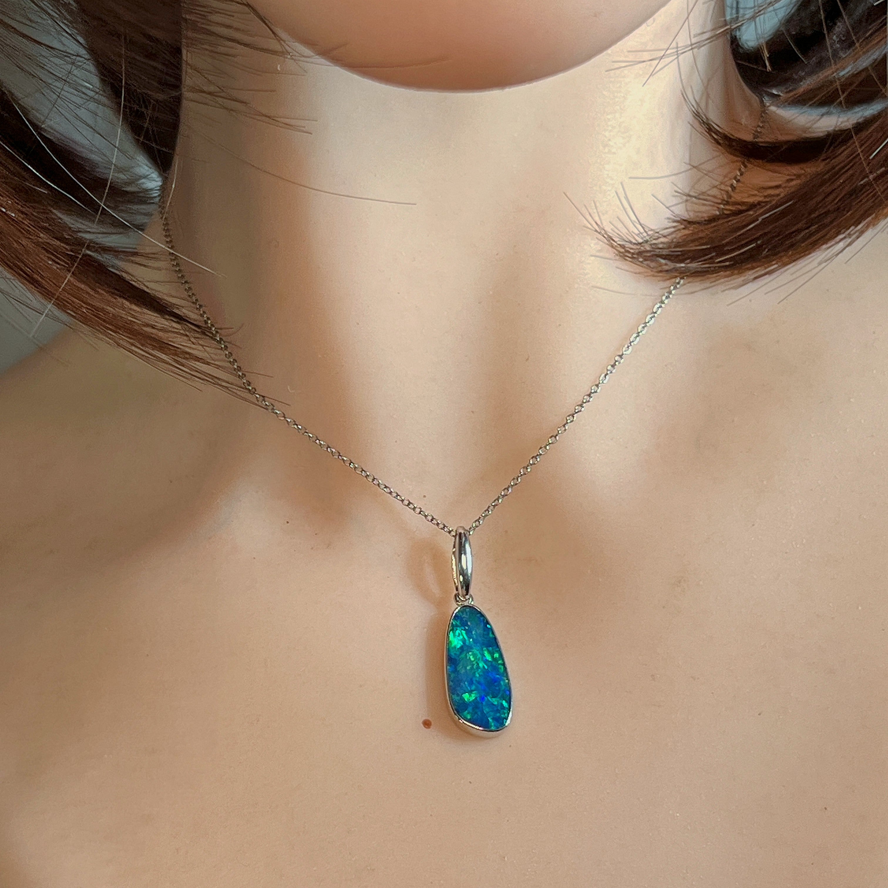 Opal doublet pendant worn at the neck, close view of the stone on the chain
