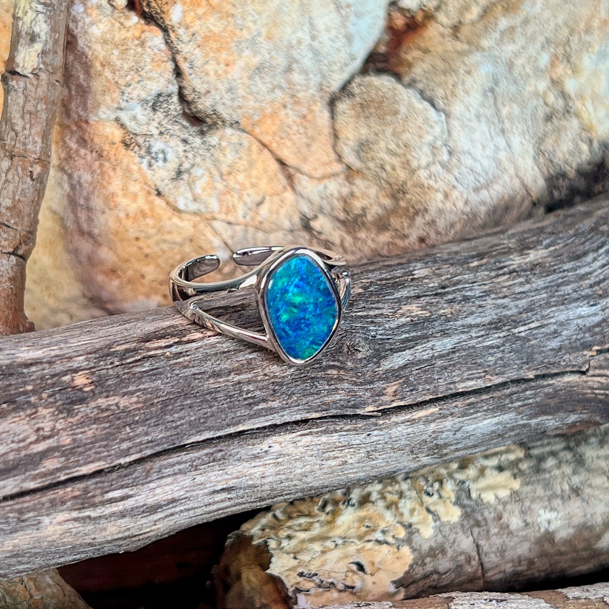 Freeform opal doublet ring in silver on driftwood against Australian sandstone