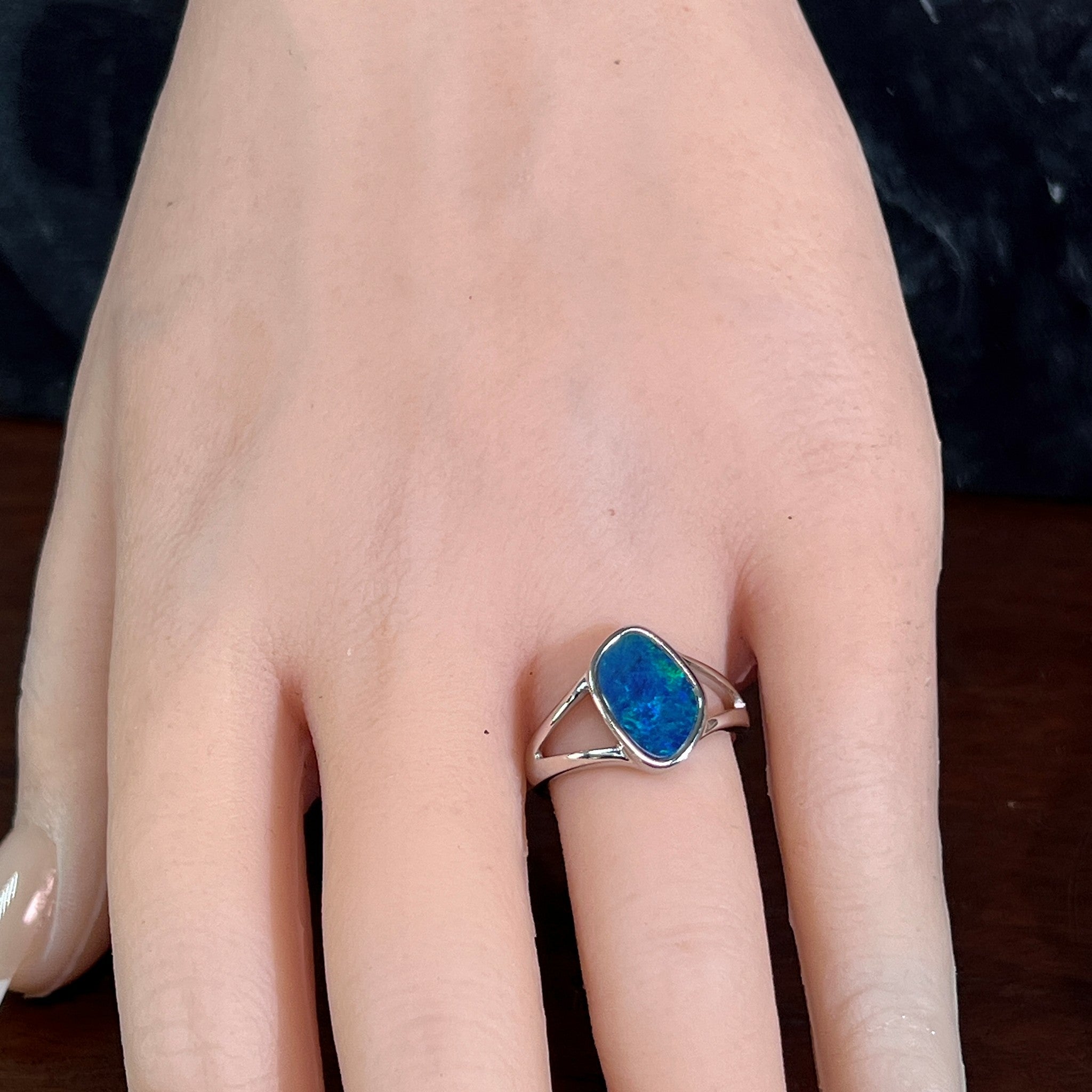 Freeform opal doublet ring in silver worn on the hand, viewed across the fingers