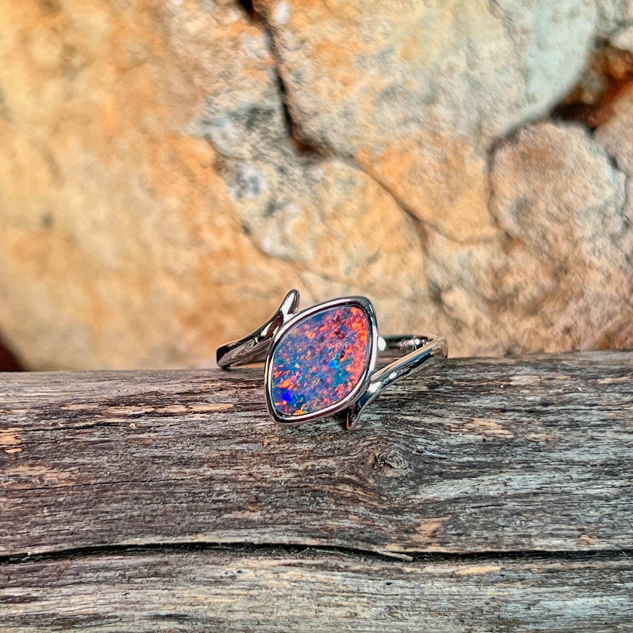 Marquise opal doublet ring in silver resting on weathered driftwood