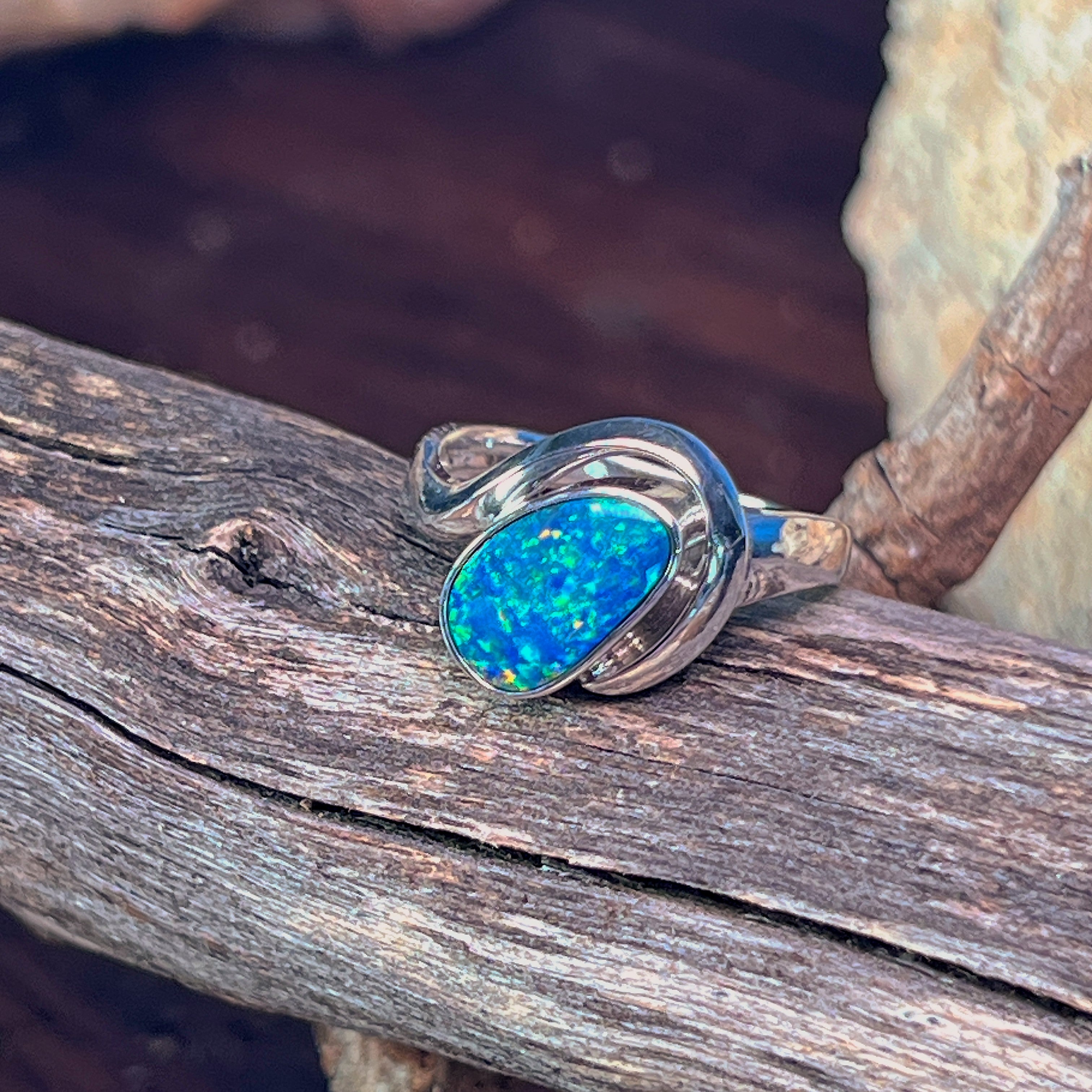 Oval opal doublet in a silver bypass setting, close view of the blue and green flash