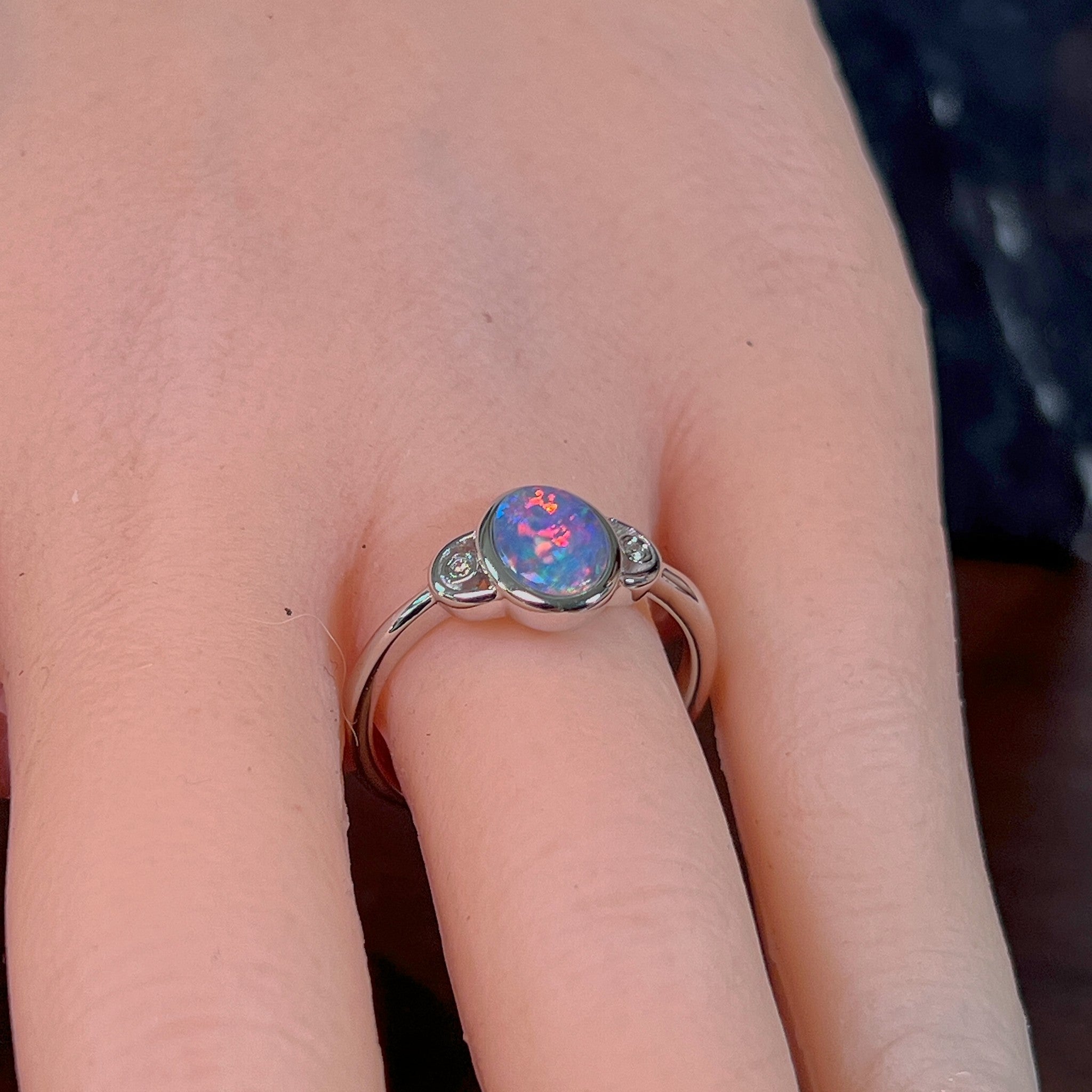 Oval opal doublet ring in silver worn on the hand, full view across the fingers
