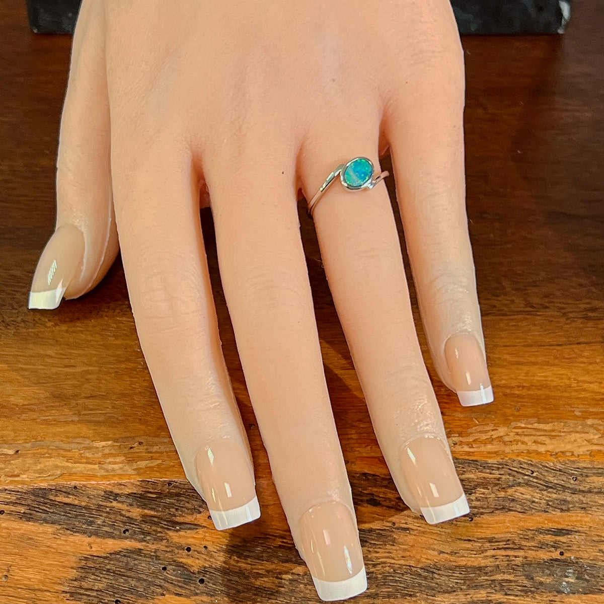 Slanted oval opal doublet ring in silver worn on the hand, full view across the fingers