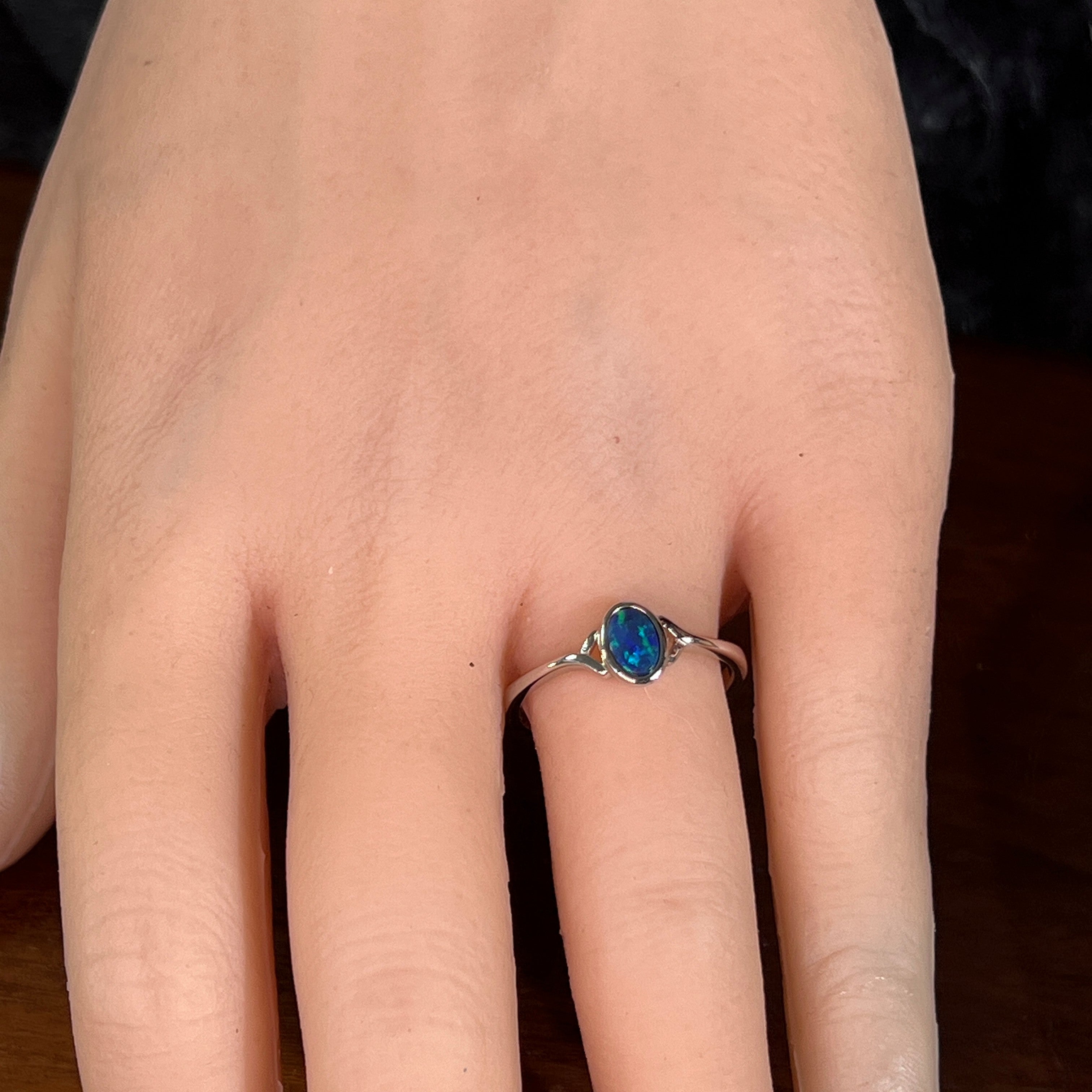 Deep green opal doublet ring in silver worn on the hand, viewed across the fingers