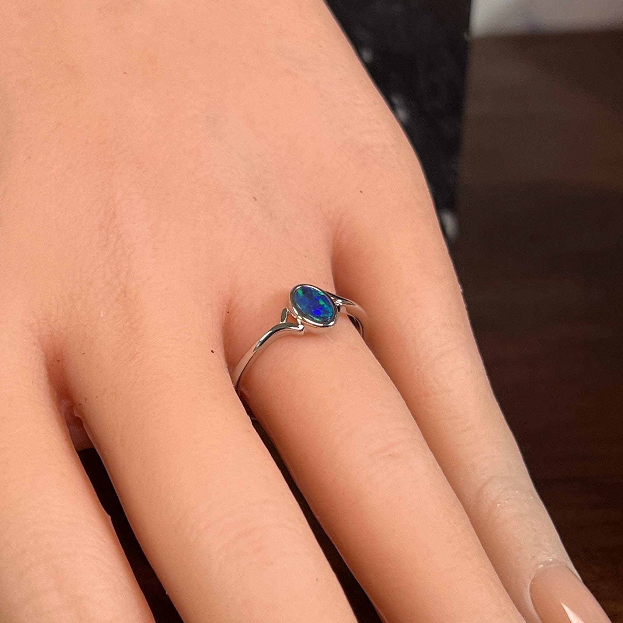Deep green opal doublet ring in silver on the hand, angled to catch the green and black play of colour