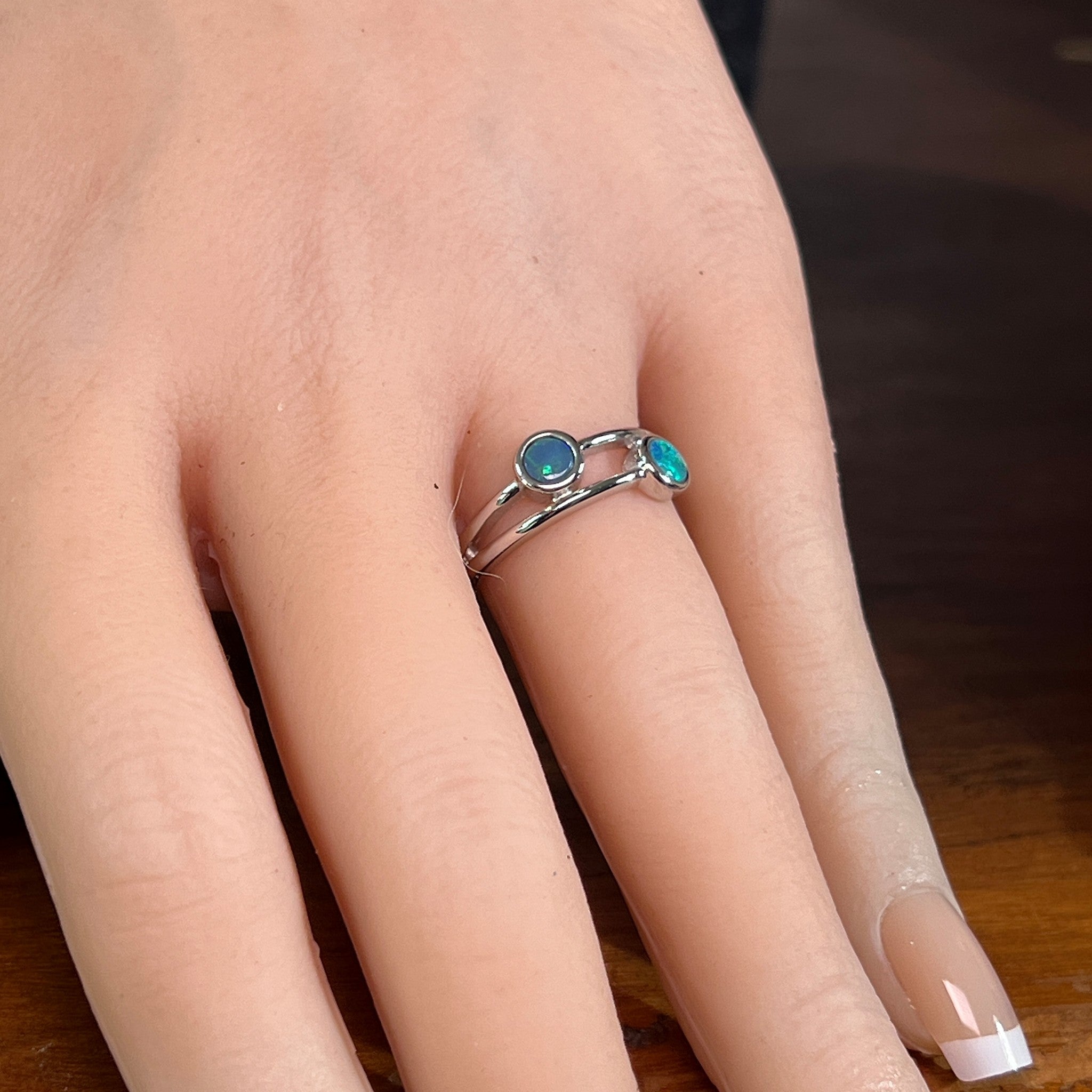 Silver ring with two round opal doublets worn on the hand, showing its scale on the finger