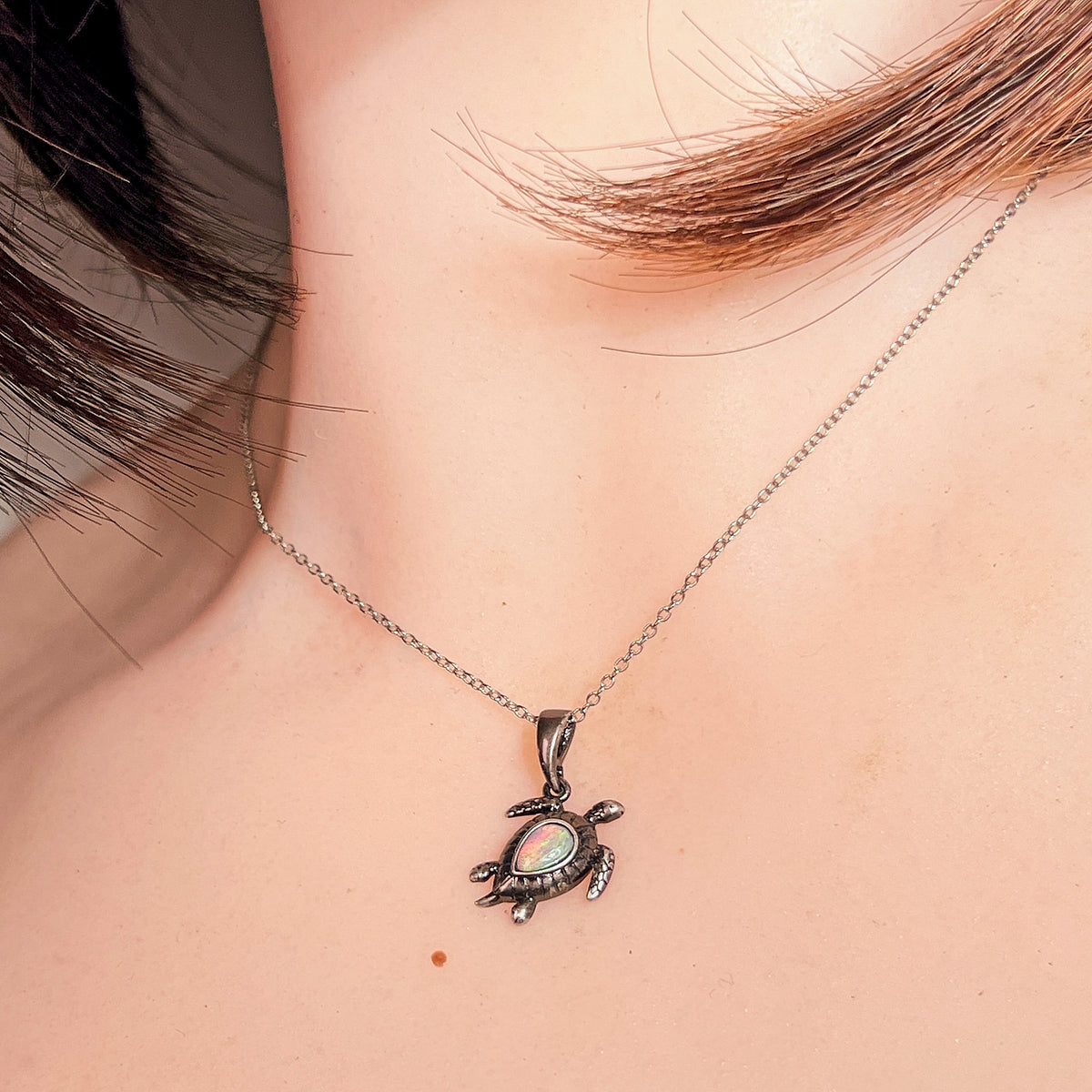 Australian crystal opal pendant worn at the neck, red, green, blue and pink play-of-colour