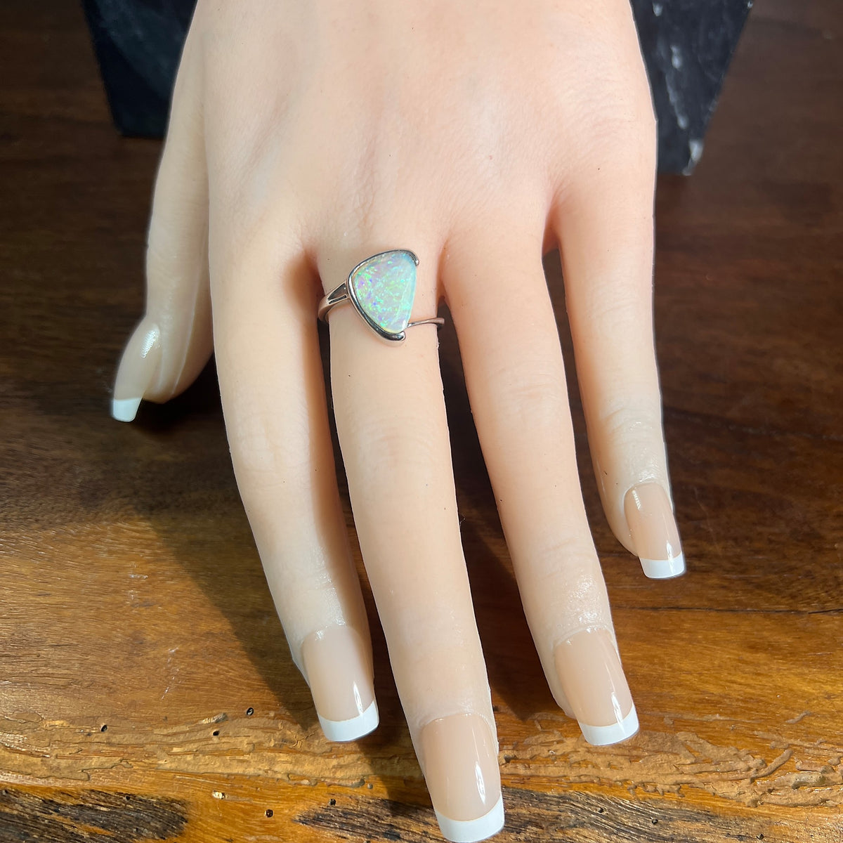 Sterling silver triangular crystal opal ring, solid Australian opal 13x10mm, green and blue, shown on a display hand