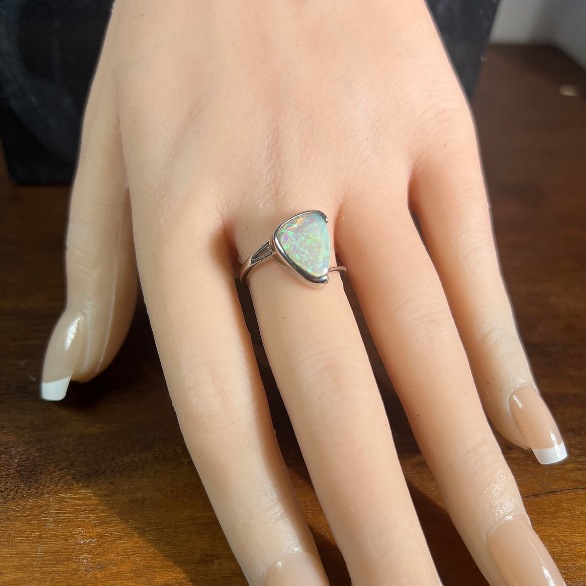 Cross over sterling silver ring with a 1.8ct solid crystal opal, green and blue play-of-colour, on a display hand