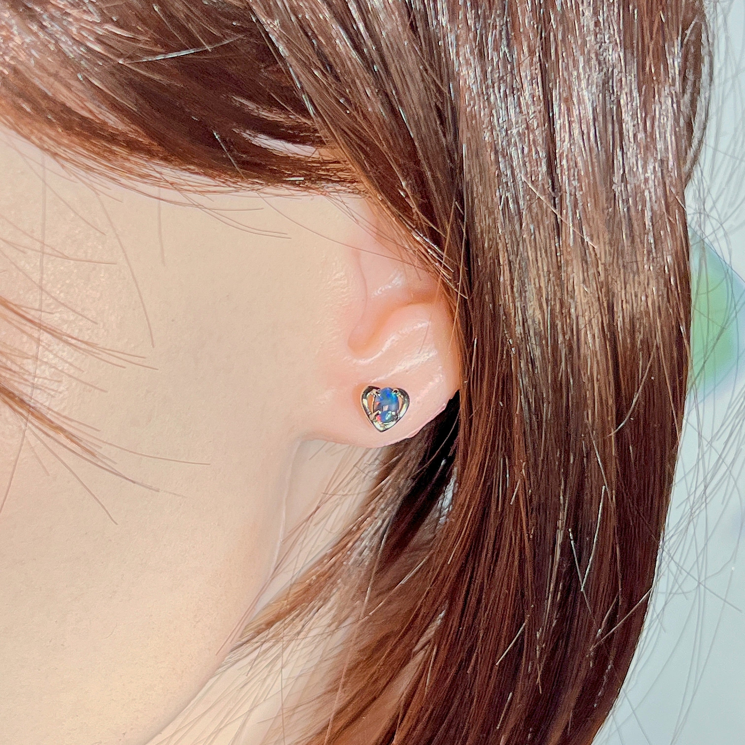 Opal triplet heart stud worn on the ear beneath loose hair