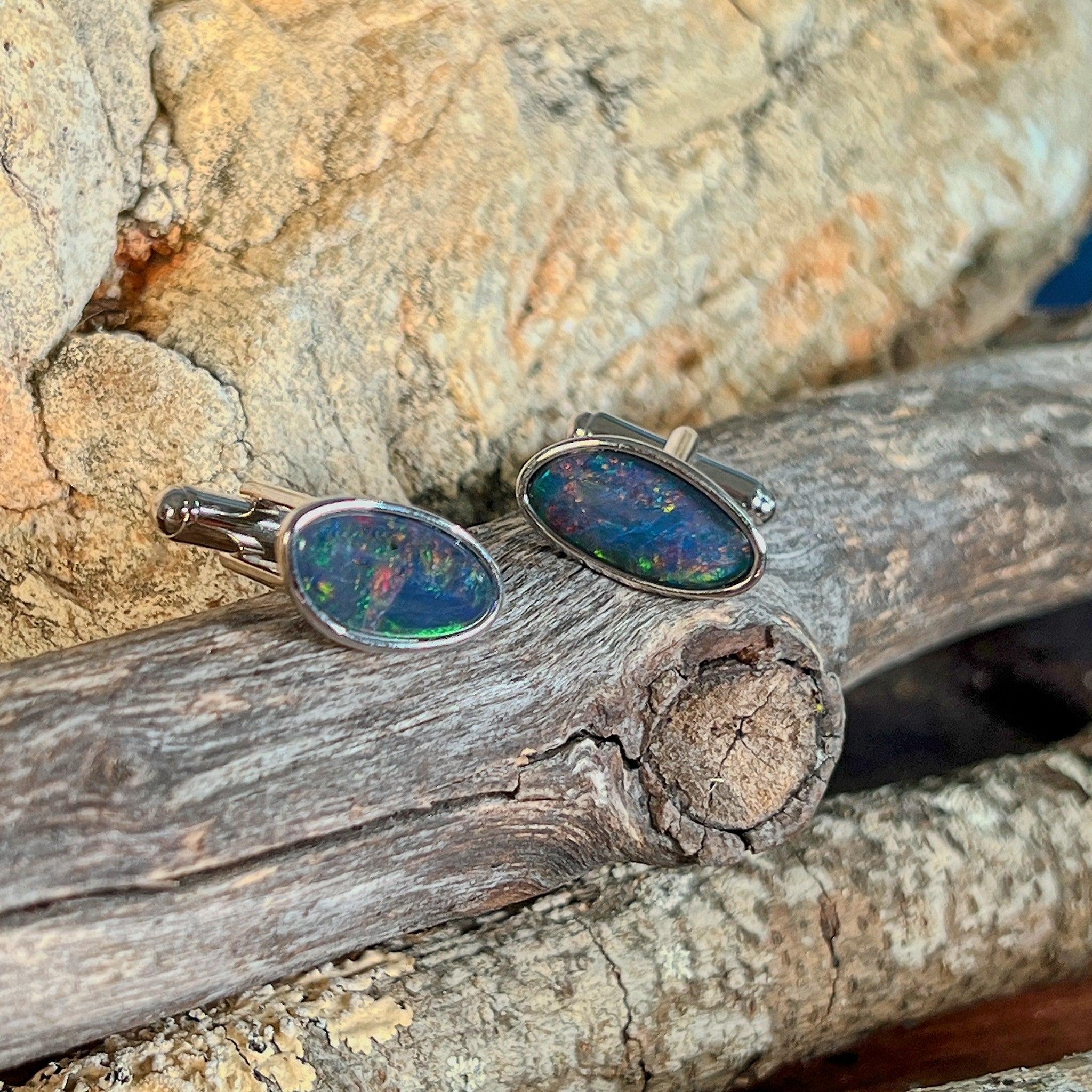 Pair of opal triplet cufflinks in silver on driftwood against Australian sandstone