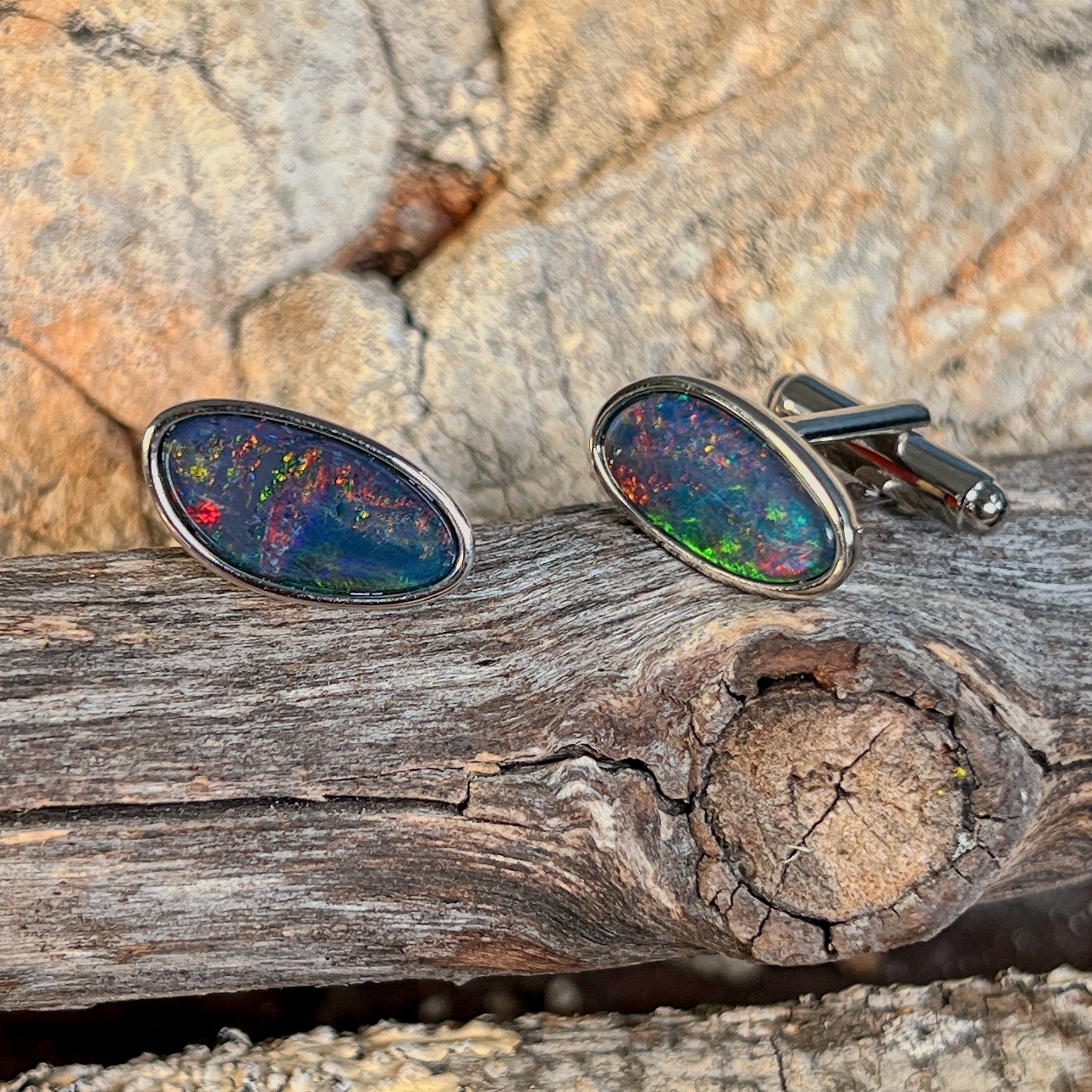 Pair of opal triplet cufflinks in silver on driftwood, the freeform opal triplet catching the light