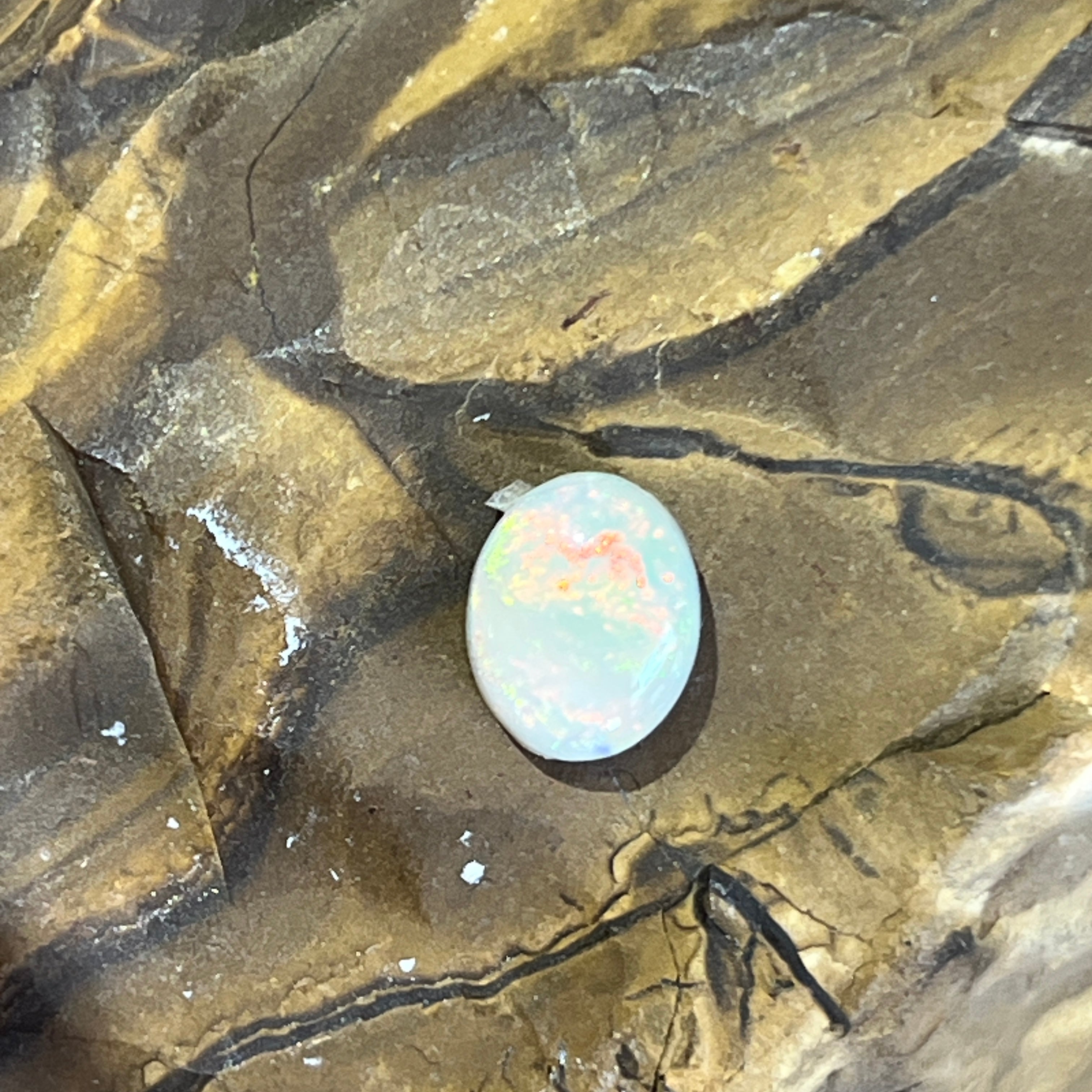 1.1ct Australian white opal oval, pink and orange flecks against a milky white body