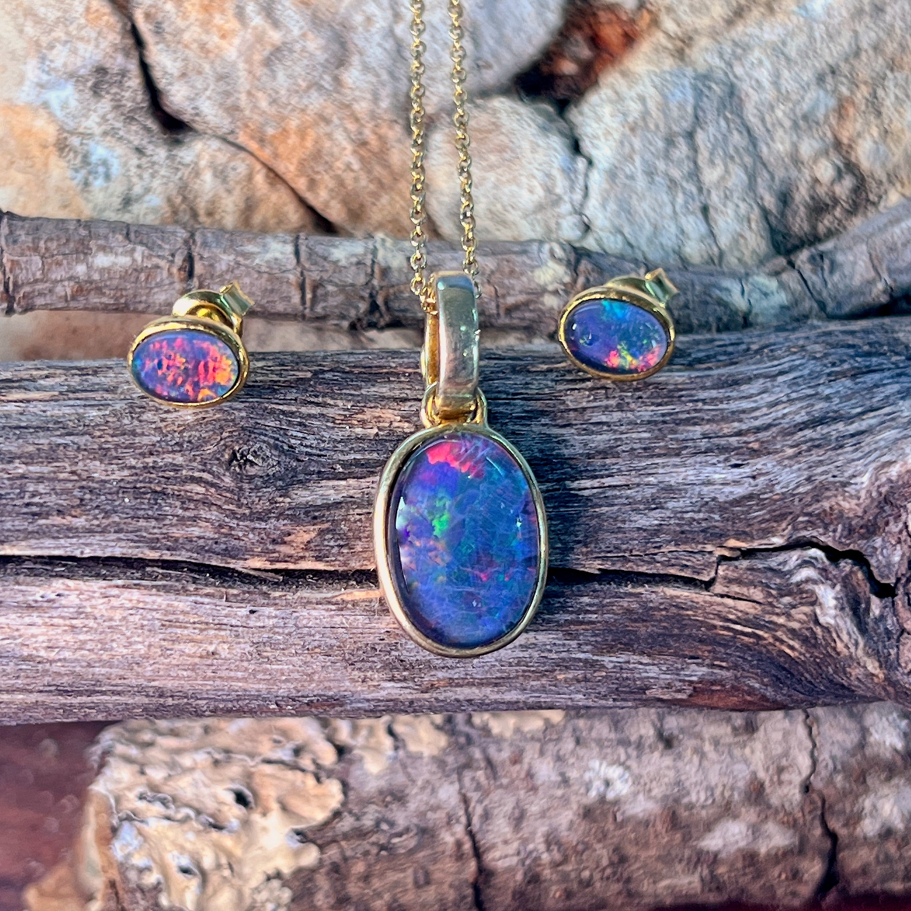Gold-plated silver bezel-set opal triplet pendant and studs on weathered driftwood