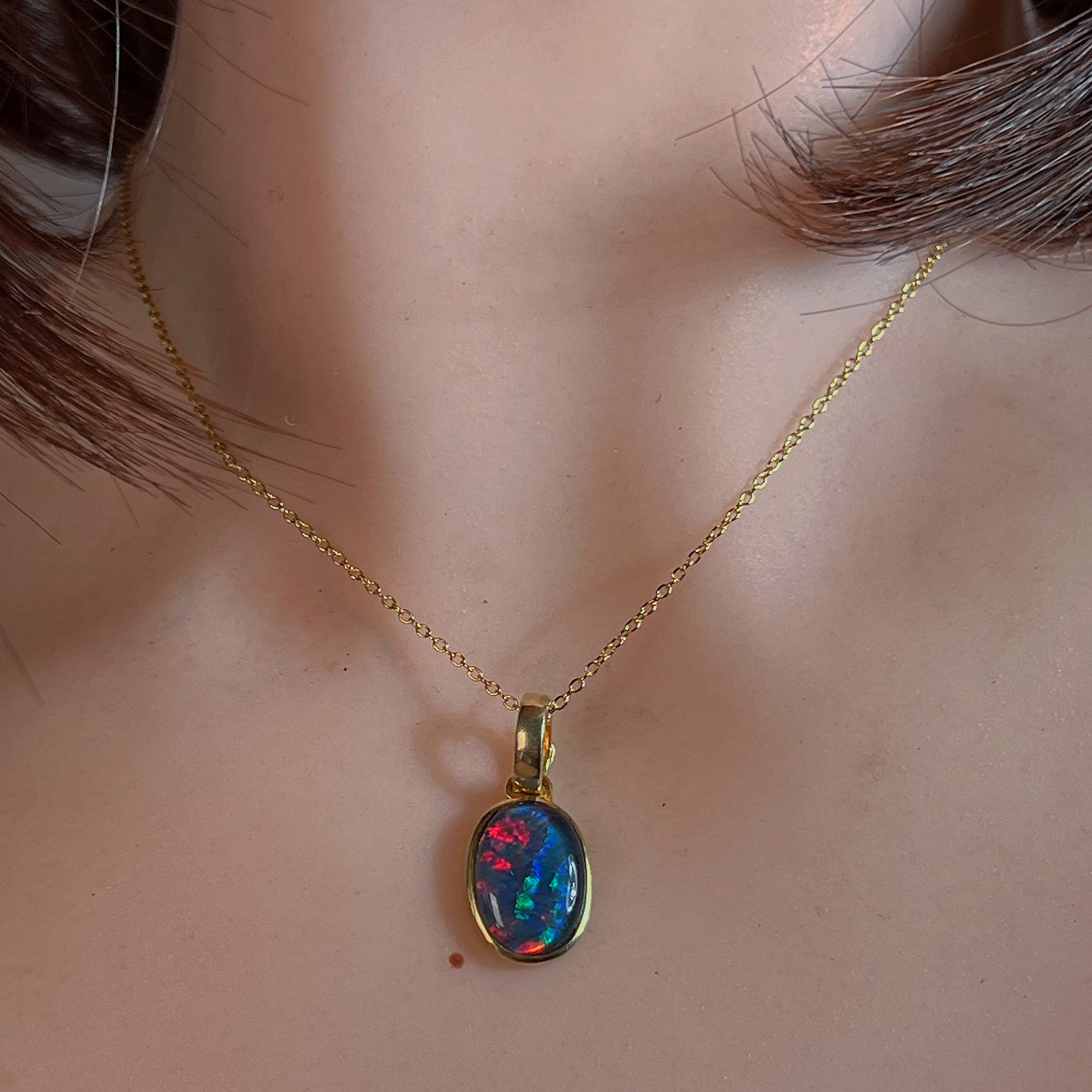 Bezel-set opal triplet pendant worn at the neck on a fine gold-plated chain