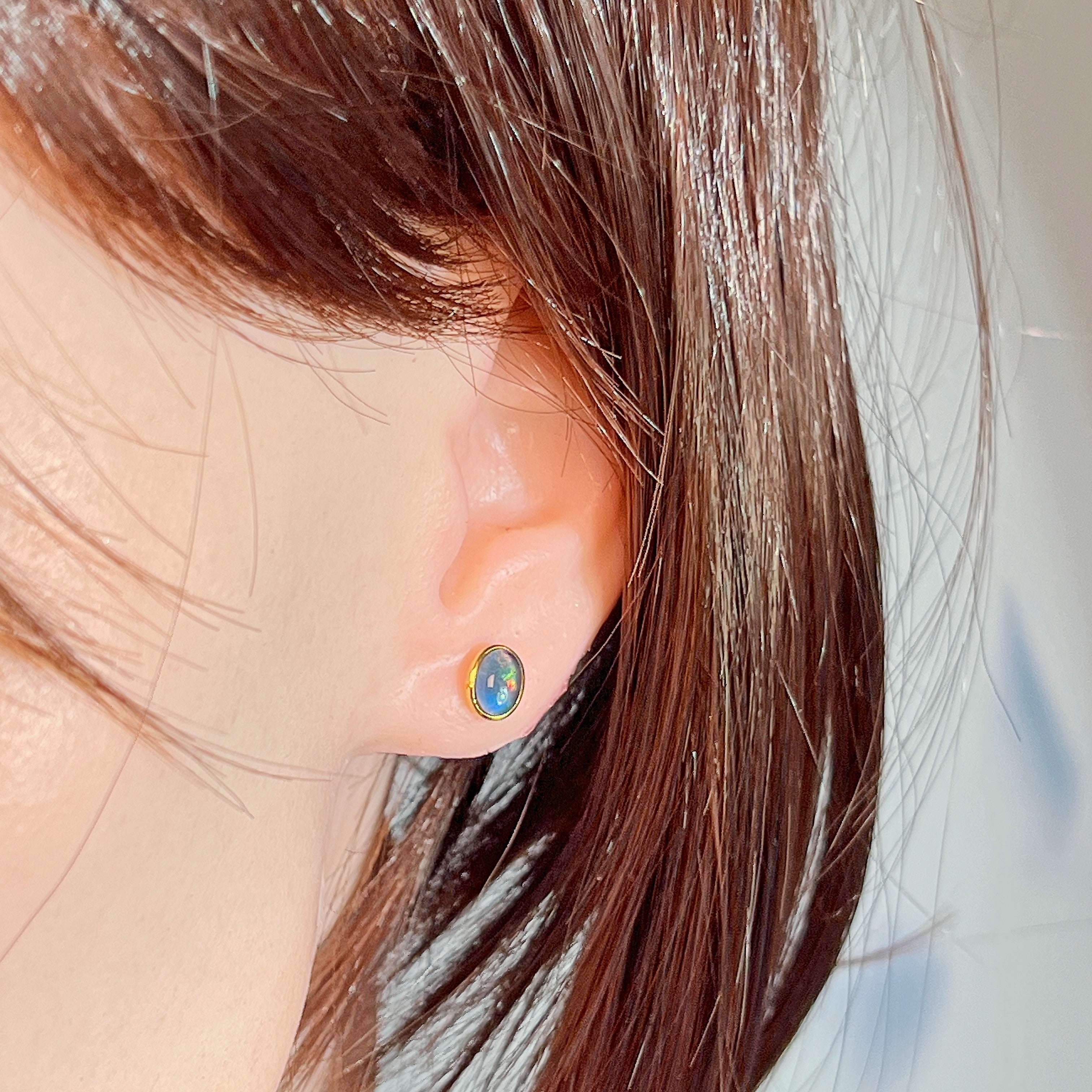 Opal triplet stud in gold-plated silver worn on the ear, side profile view