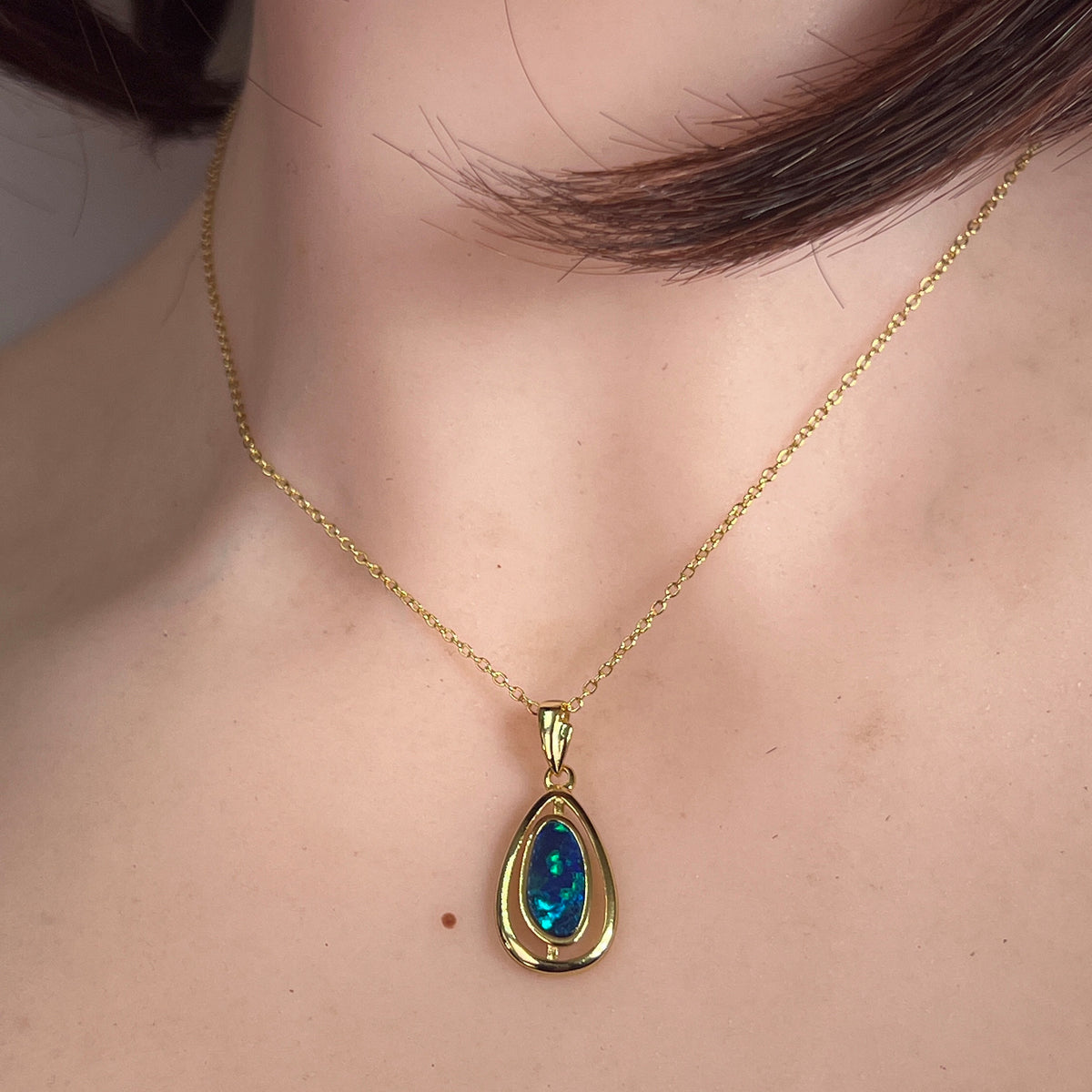 freeform Australian opal doublet pendant in yellow gold-plated silver, worn at the neck