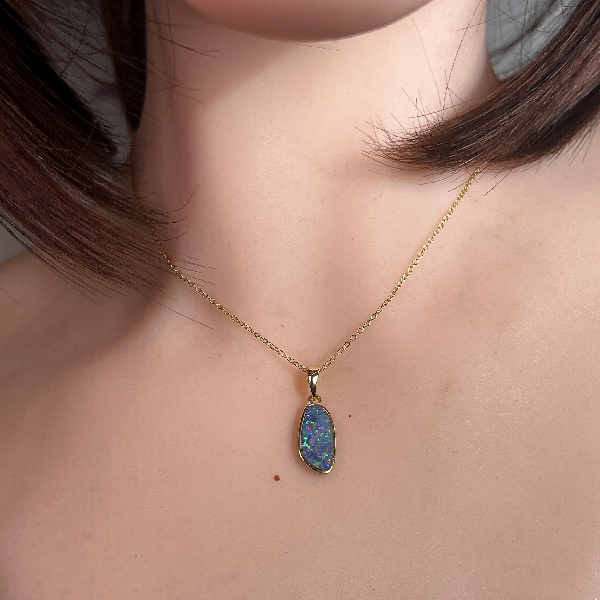 Australian opal doublet pendant worn at the neck, yellow gold-plated silver, 15 x 7mm freeform stone