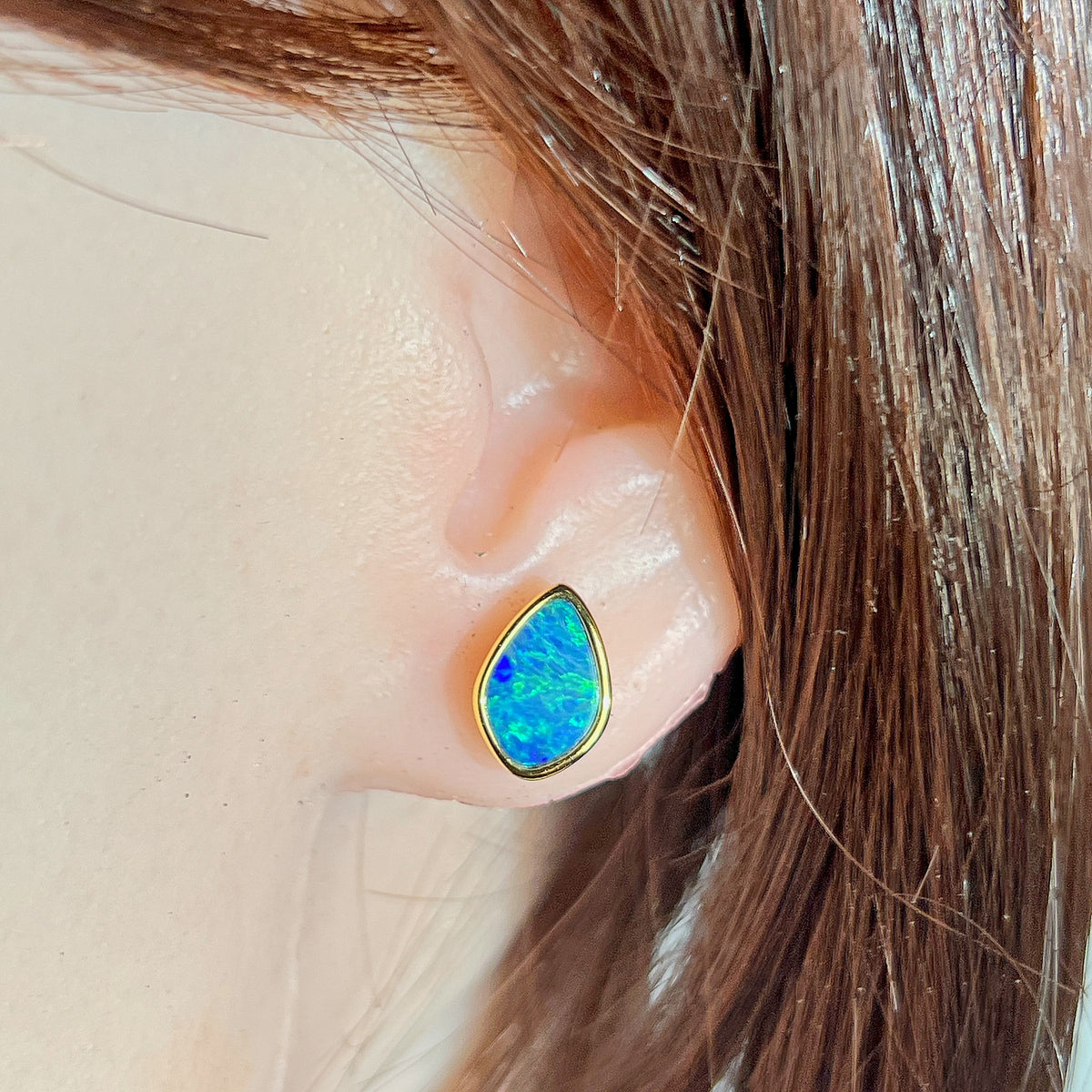Australian opal doublet earrings worn on the ear, green and blue play-of-colour