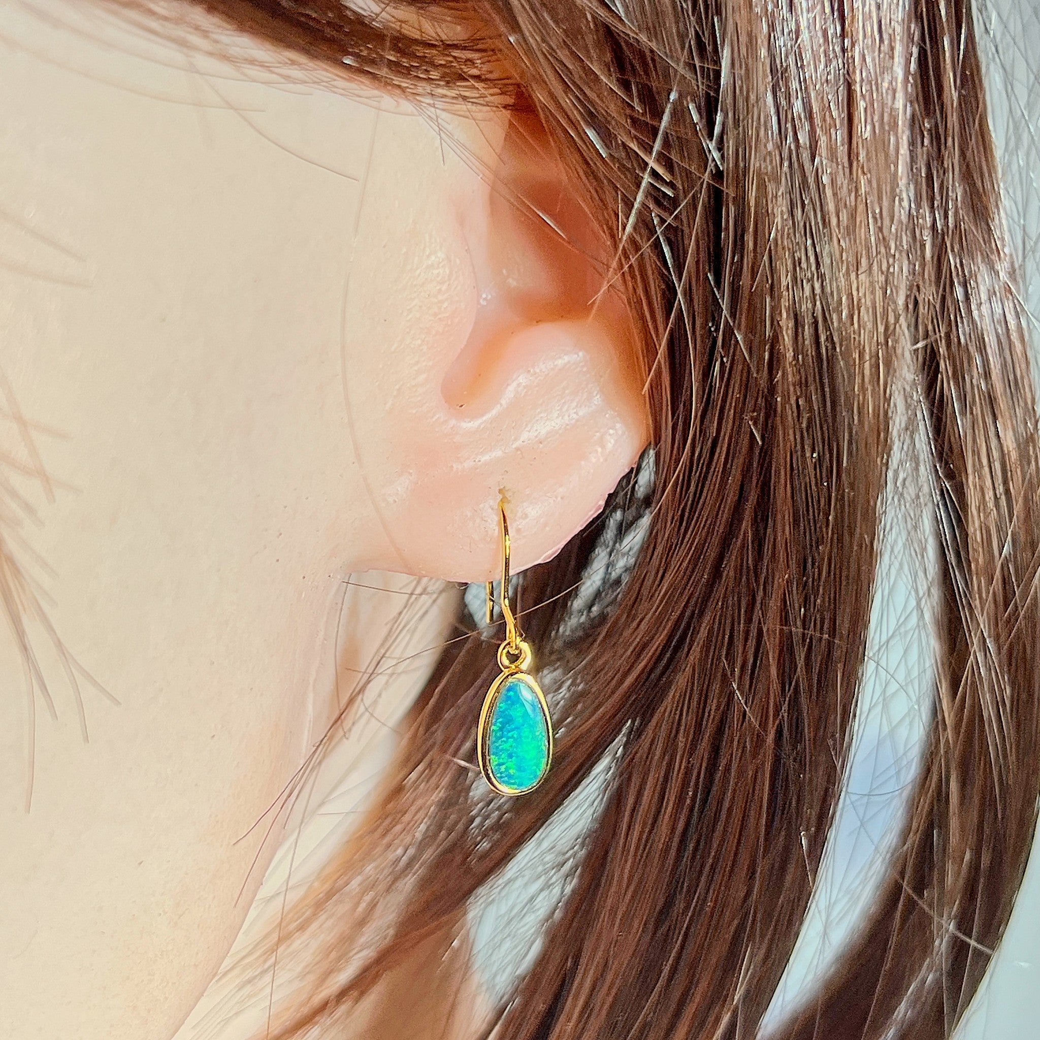 Australian opal doublet earrings worn on the ear, green and yellow play-of-colour
