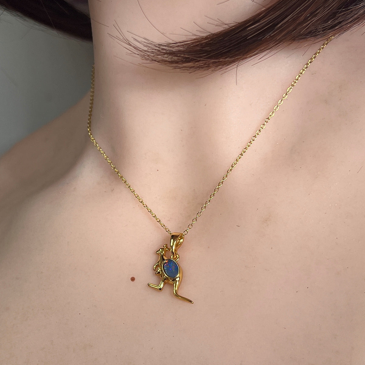 6 x 4mm oval Australian opal doublet pendant worn at the neck, yellow gold-plated silver