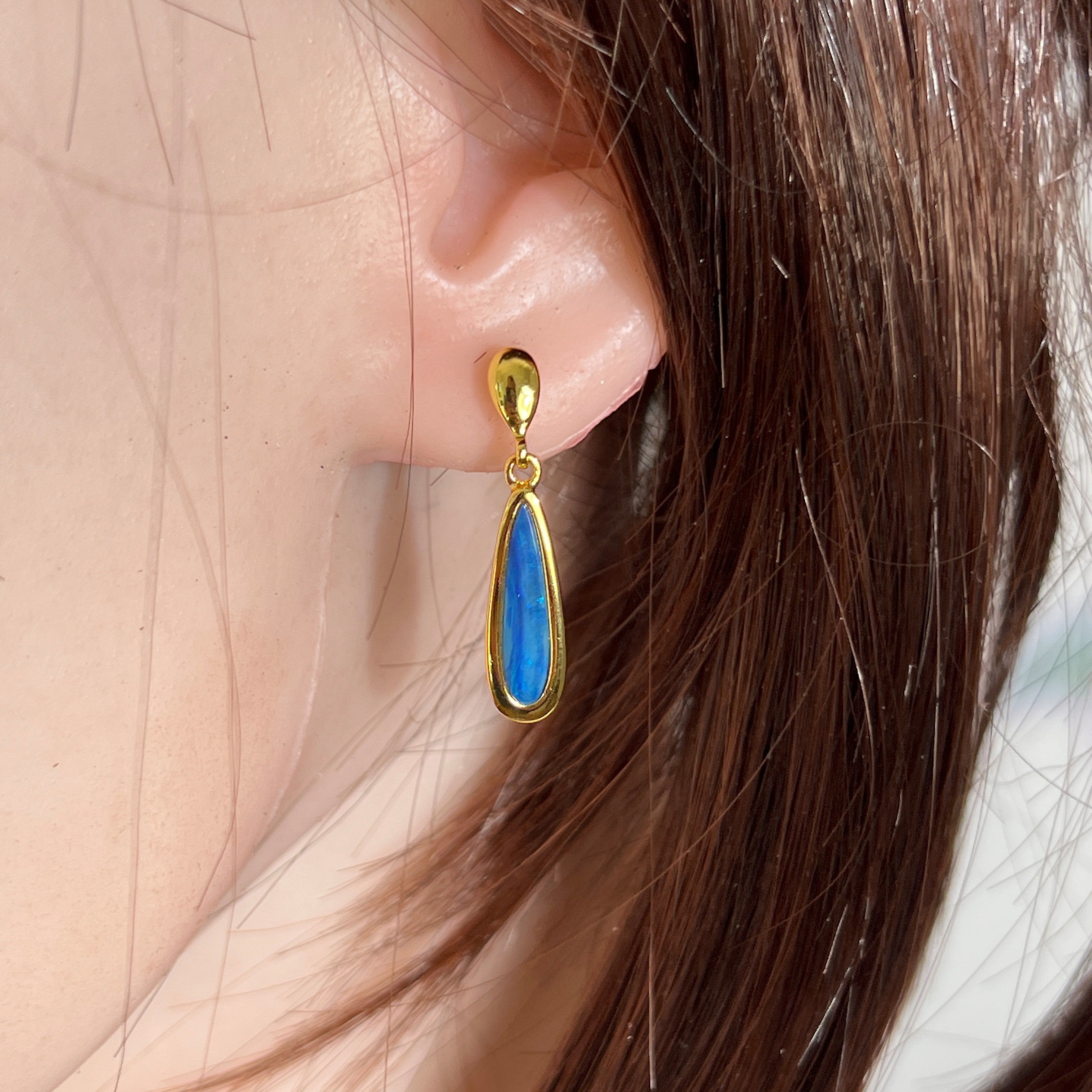 pear-shaped Australian opal doublet earrings in yellow gold-plated silver, worn on the ear
