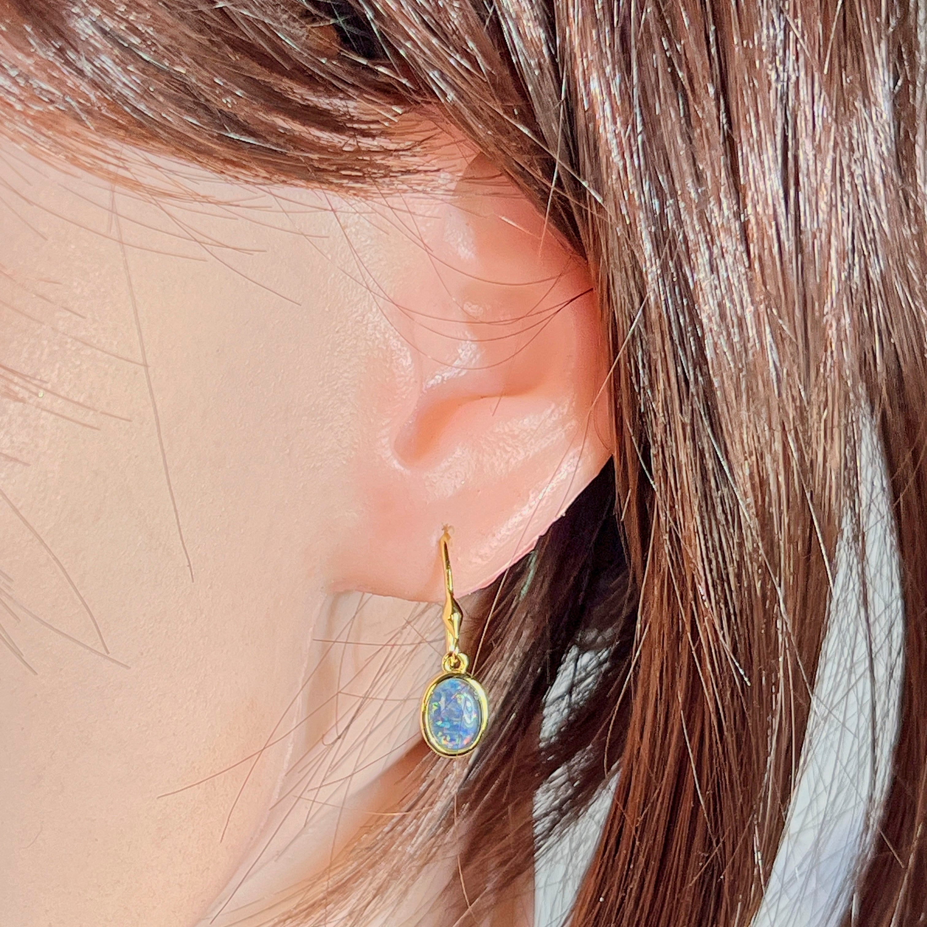 Yellow gold plated opal triplet dangling earring worn on the ear