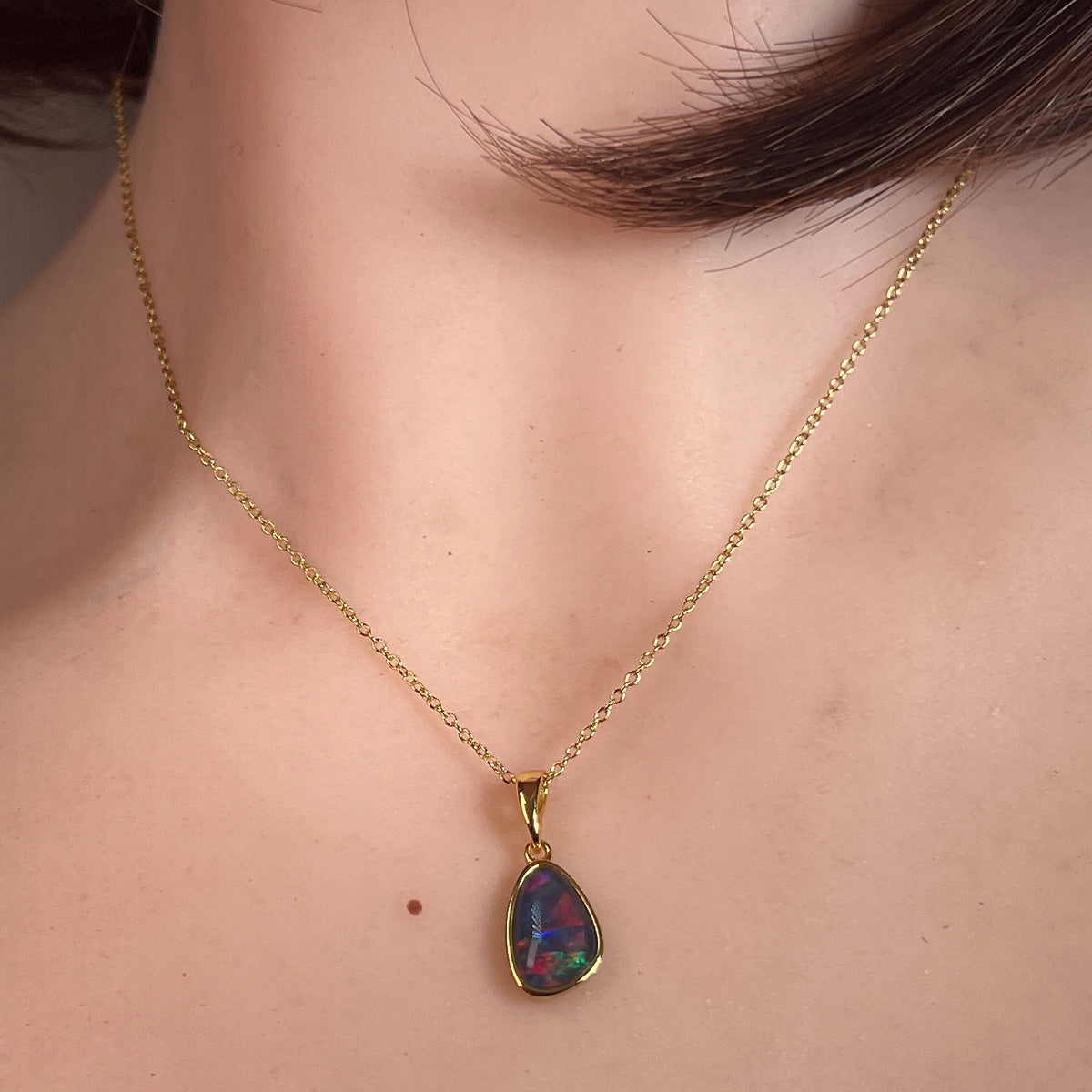 11 x 8mm freeform Australian opal triplet pendant worn at the neck, yellow gold-plated silver