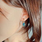 Multicolour opal doublet drop earring in rose gold worn on the ear beneath loose hair