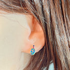 Rose gold oval opal doublet stud earring worn on the ear, showing its scale on the earlobe