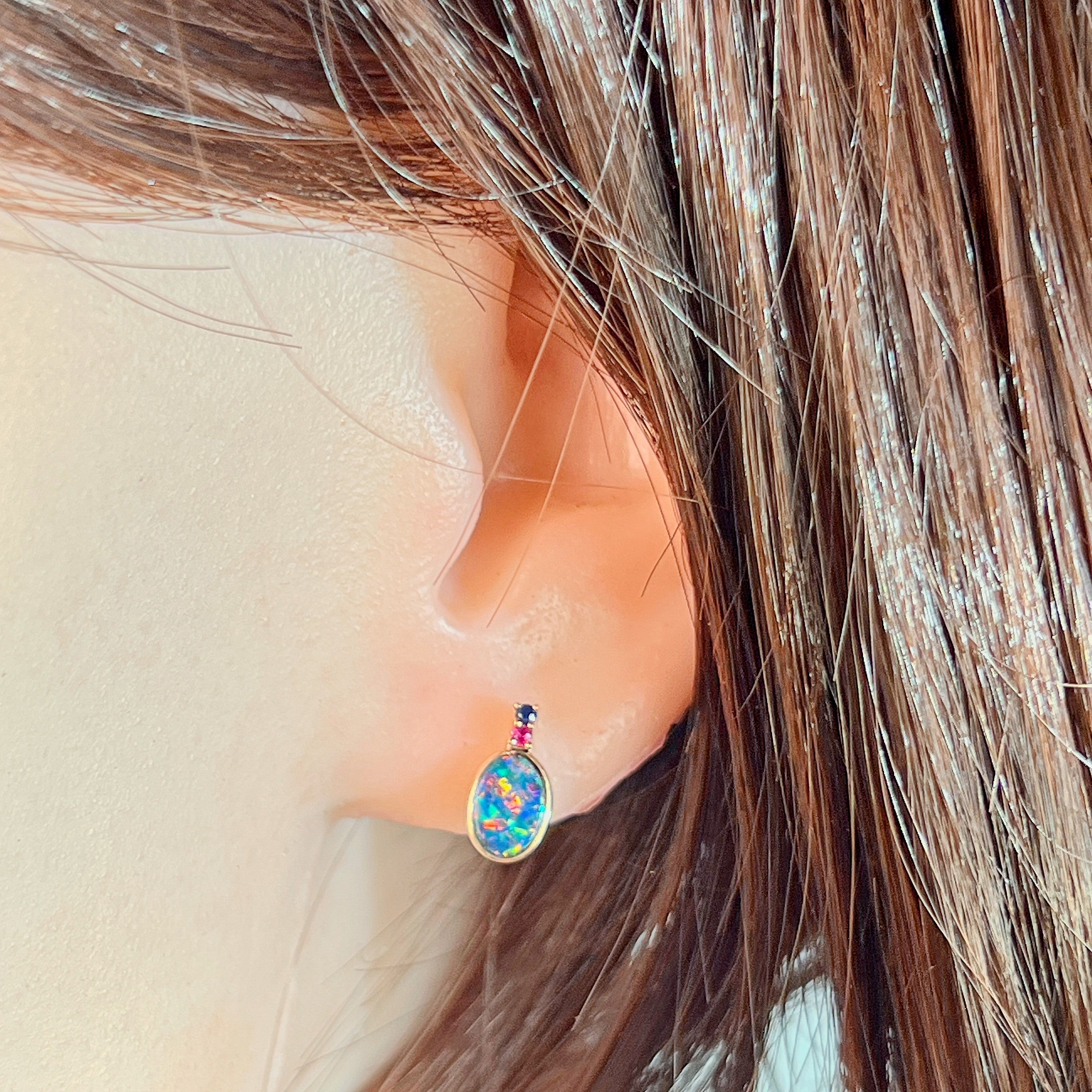 Rose gold oval opal doublet stud earring worn on the ear, showing its scale on the earlobe